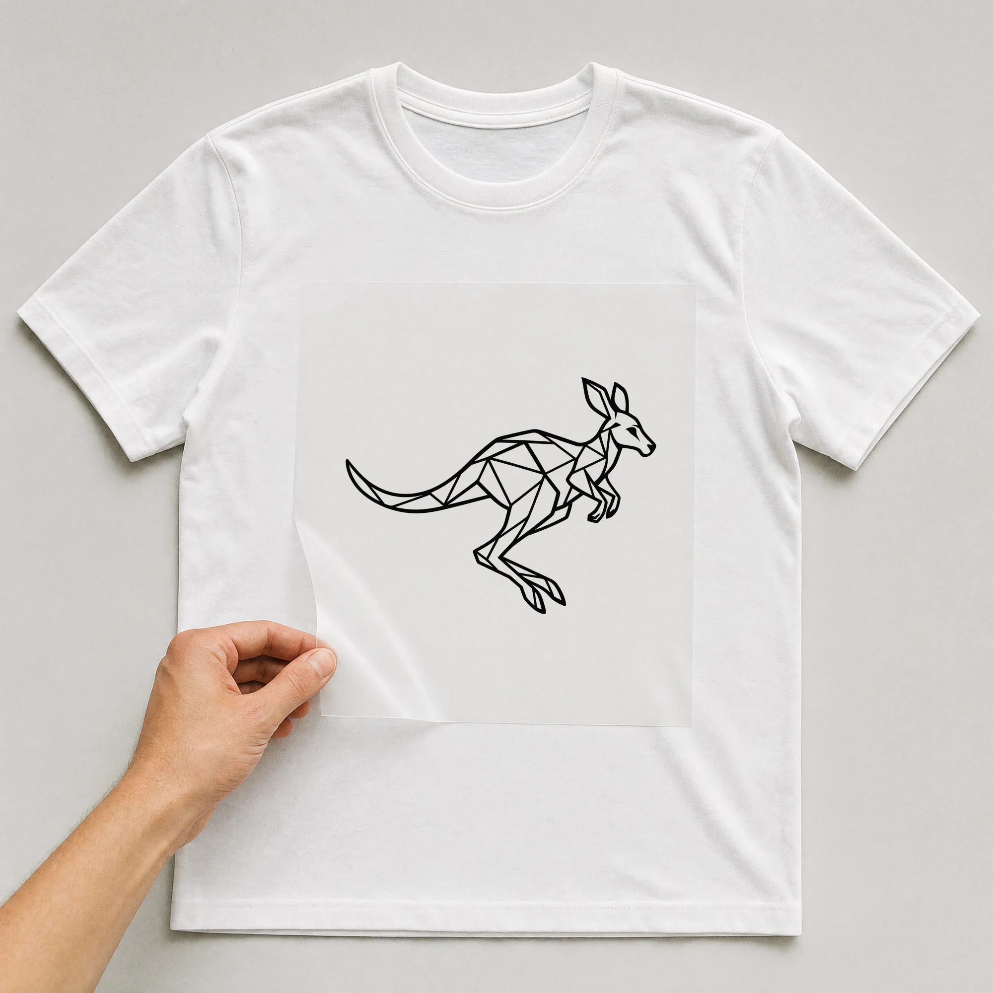 Bügelbild „Polygon Känguru“ auf weißem T-Shirt, Folie wird aufgelegt