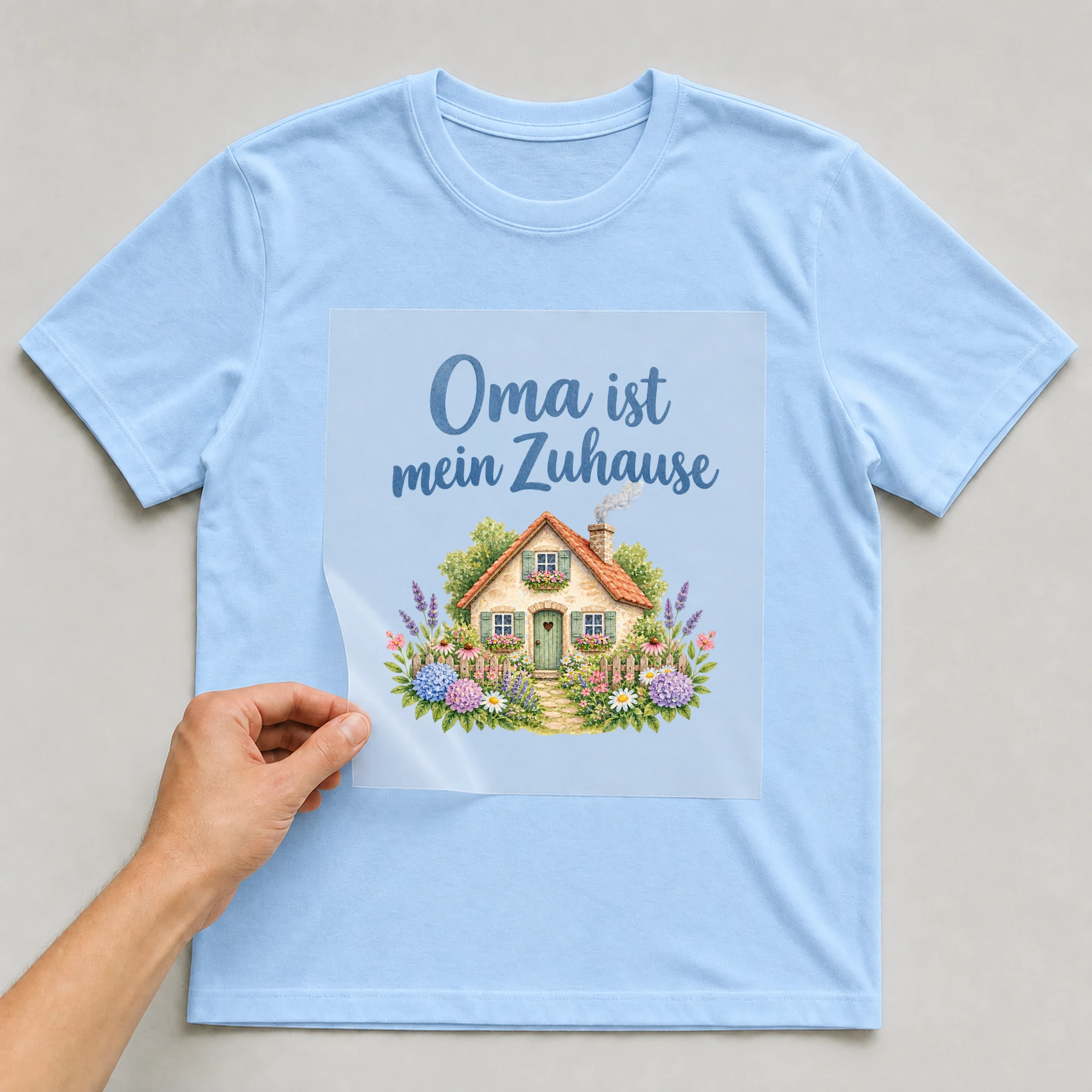 Bügelbild „Oma ist mein Zuhause“ auf babyblauem T-Shirt, Folie wird aufgelegt