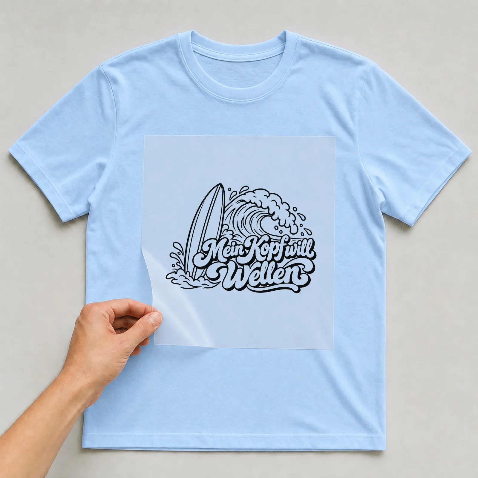 Bügelbild „Mein Kopf will Wellen“ auf hellblauem T-Shirt, Folie wird aufgelegt