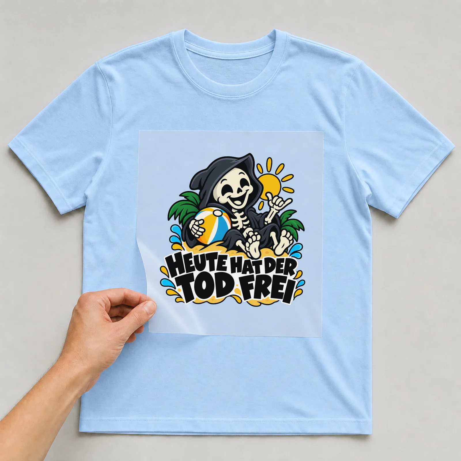 Bügelbild „Heute hat der Tod frei“ auf hellblauem T-Shirt, Folie wird aufgelegt
