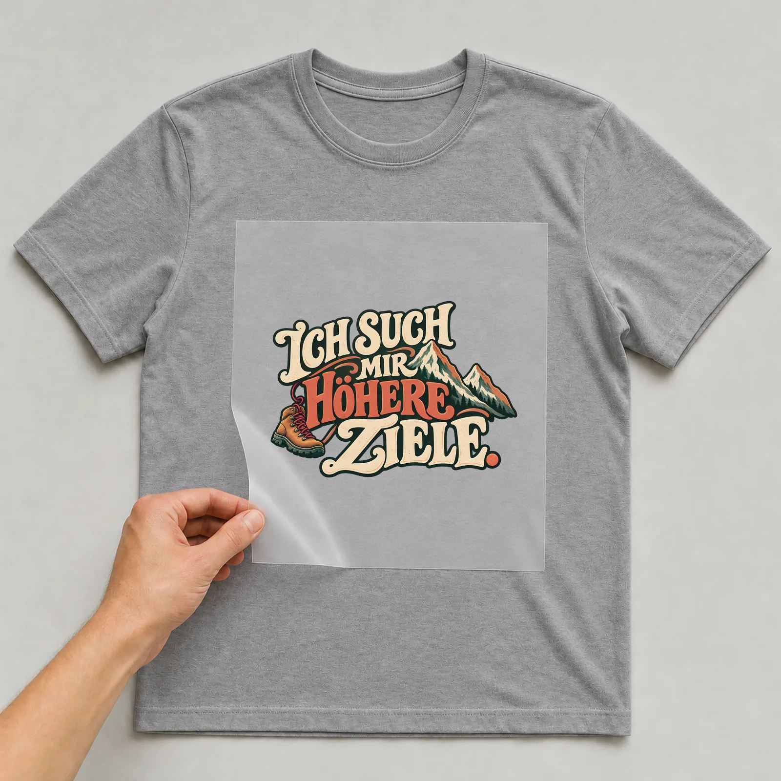 Bügelbild „Ich such mir höhere ziele“ auf grauem T-Shirt, Folie wird aufgelegt