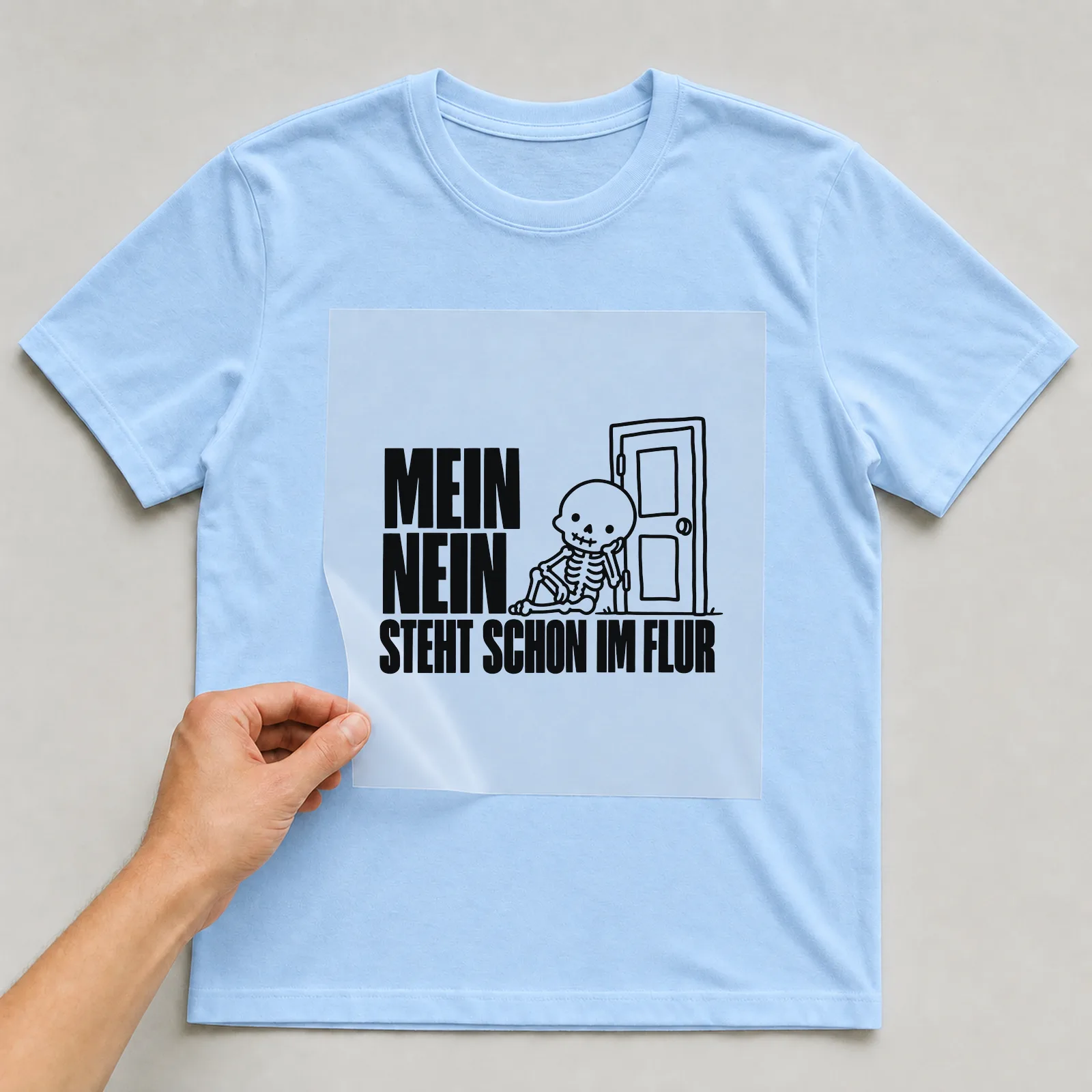Bügelbild „Mein nein steht schon im Flur“ auf hellblauem T-Shirt, Folie wird aufgelegt
