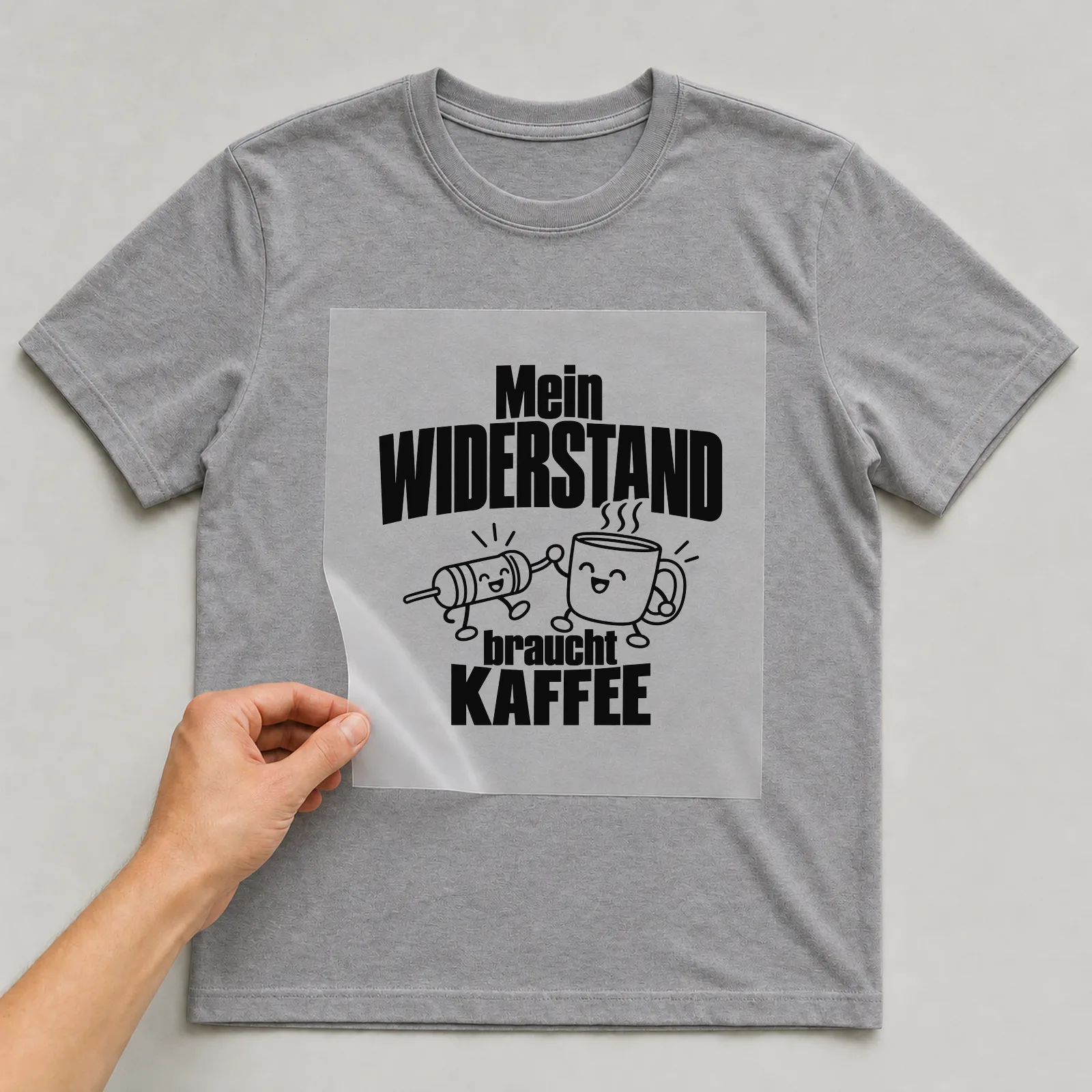 Bügelbild „Mein Widerstand braucht Kaffee“ auf grauem T-Shirt, Folie wird aufgelegt