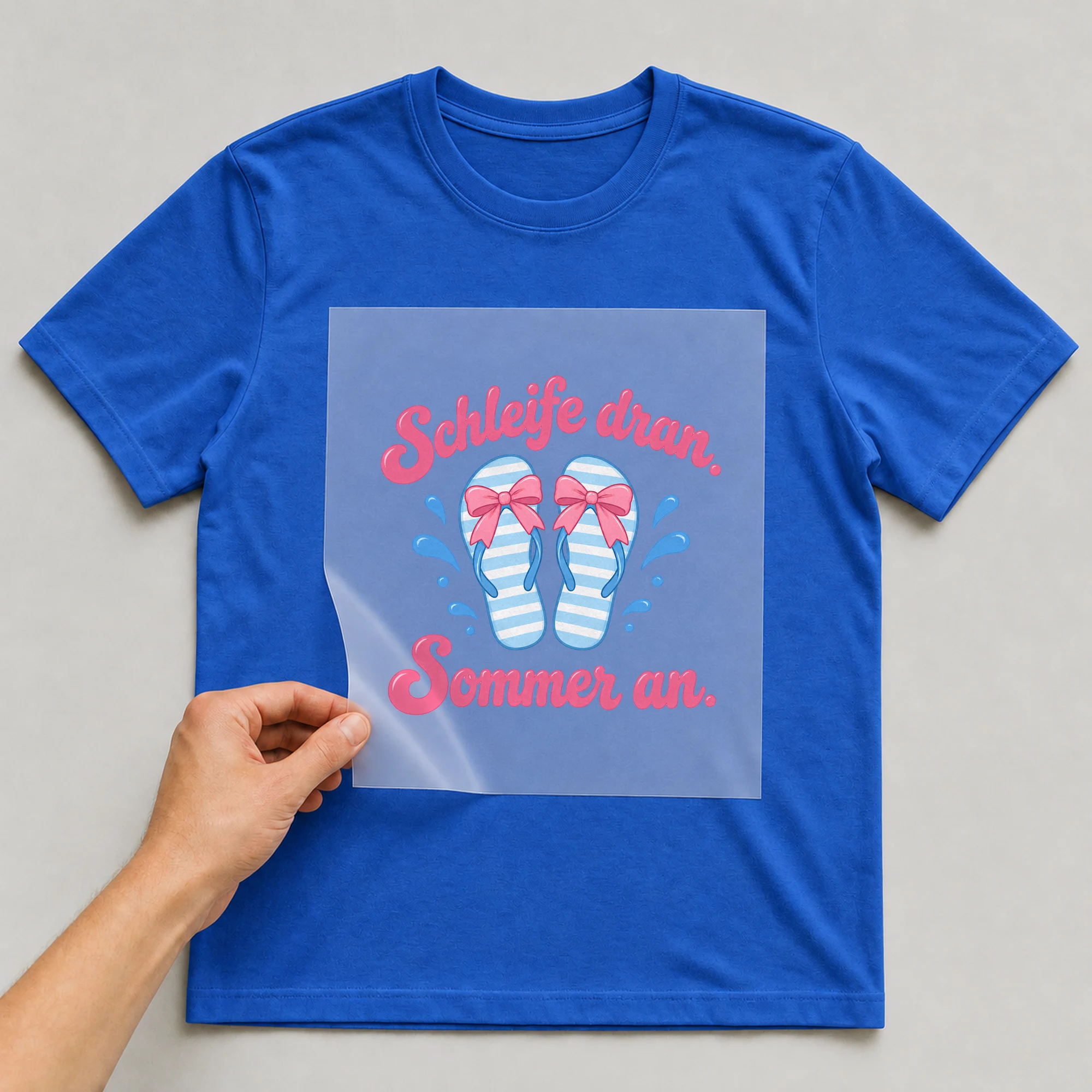Bügelbild „Schleife dran. Sommer an.“ auf blauem T-Shirt, Folie wird aufgelegt