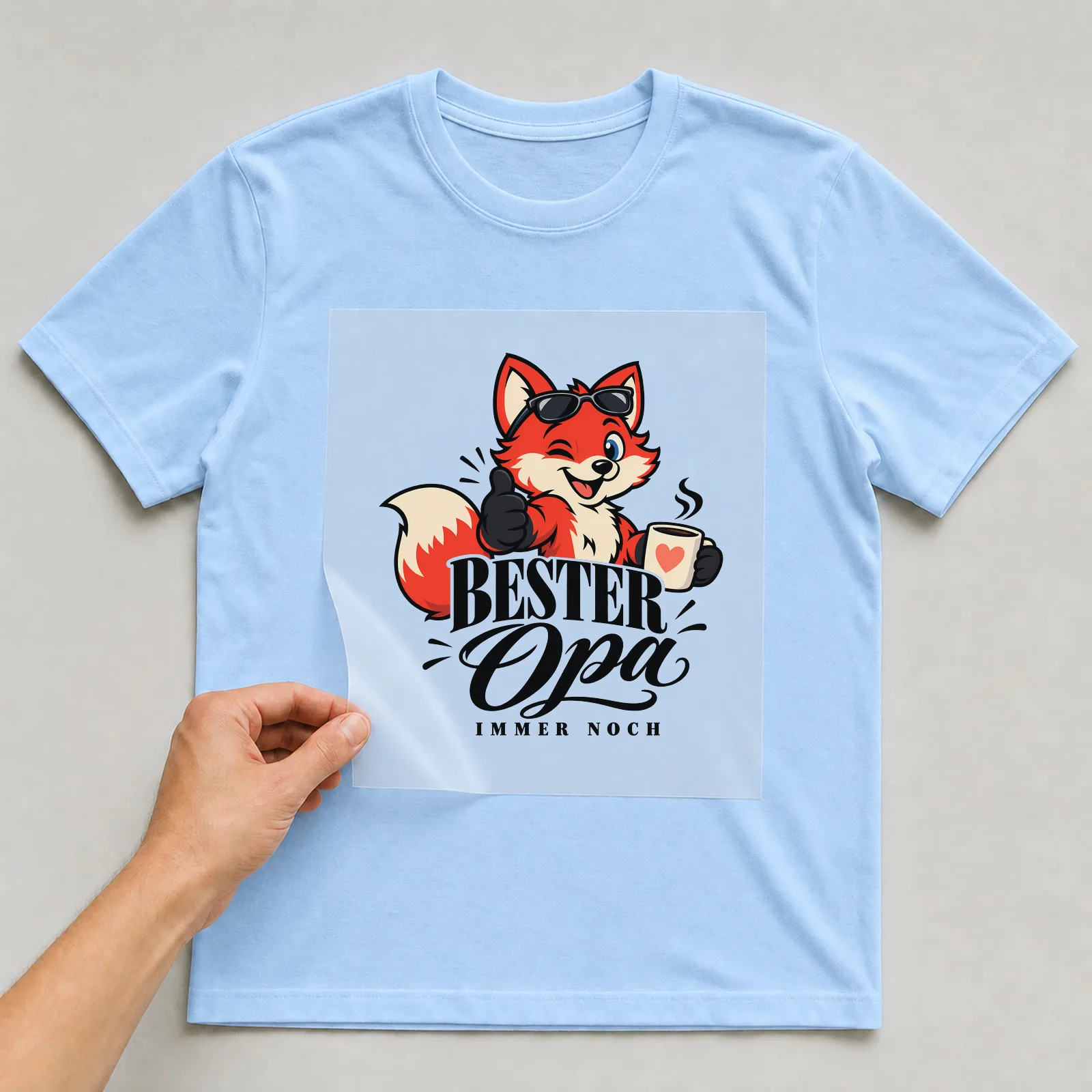 Bügelbild „Bester Opi immer noch“ auf hellblauem T-Shirt, Folie wird aufgelegt