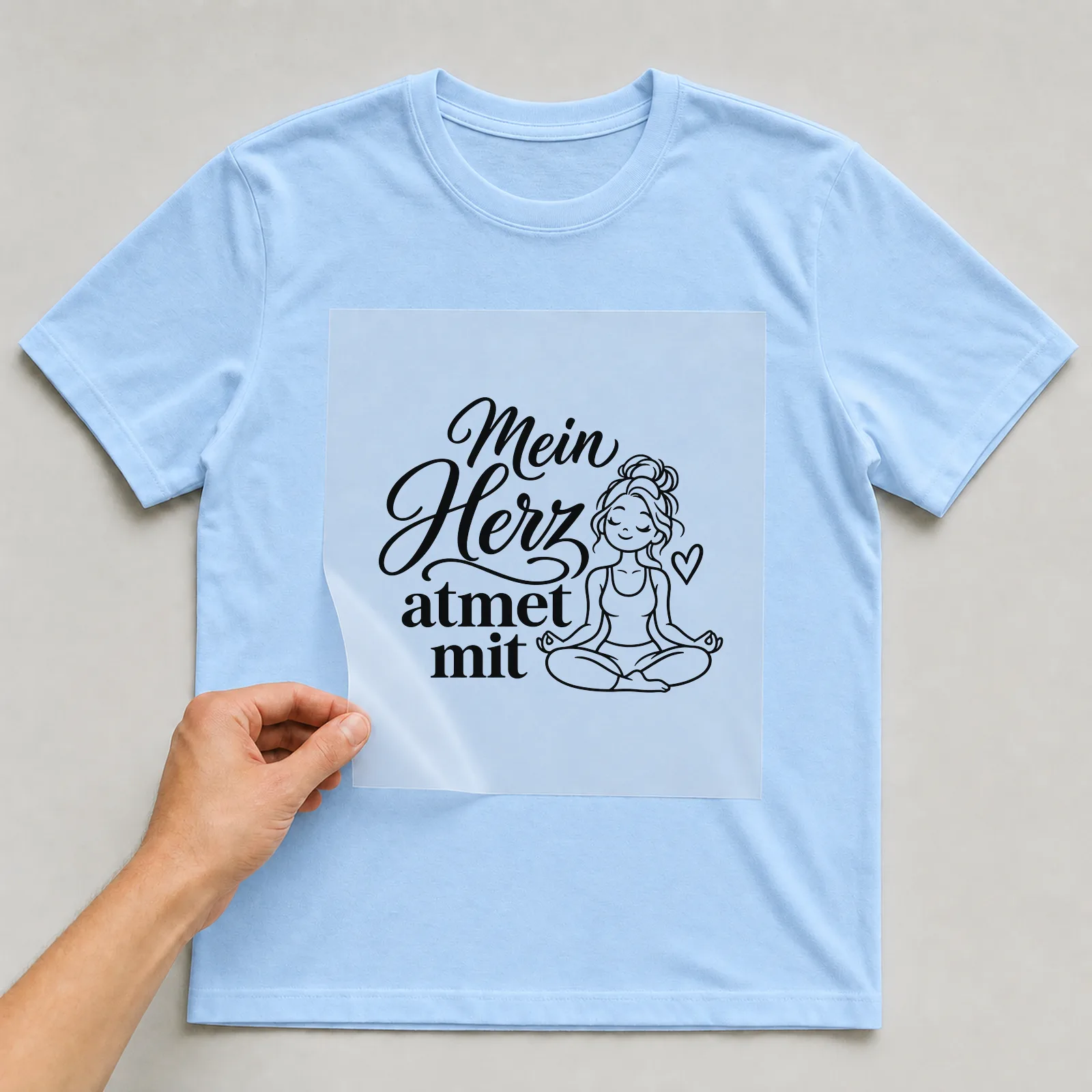 Bügelbild „Mein Herz atmet mit“ auf hellblauem T-Shirt, Folie wird aufgelegt