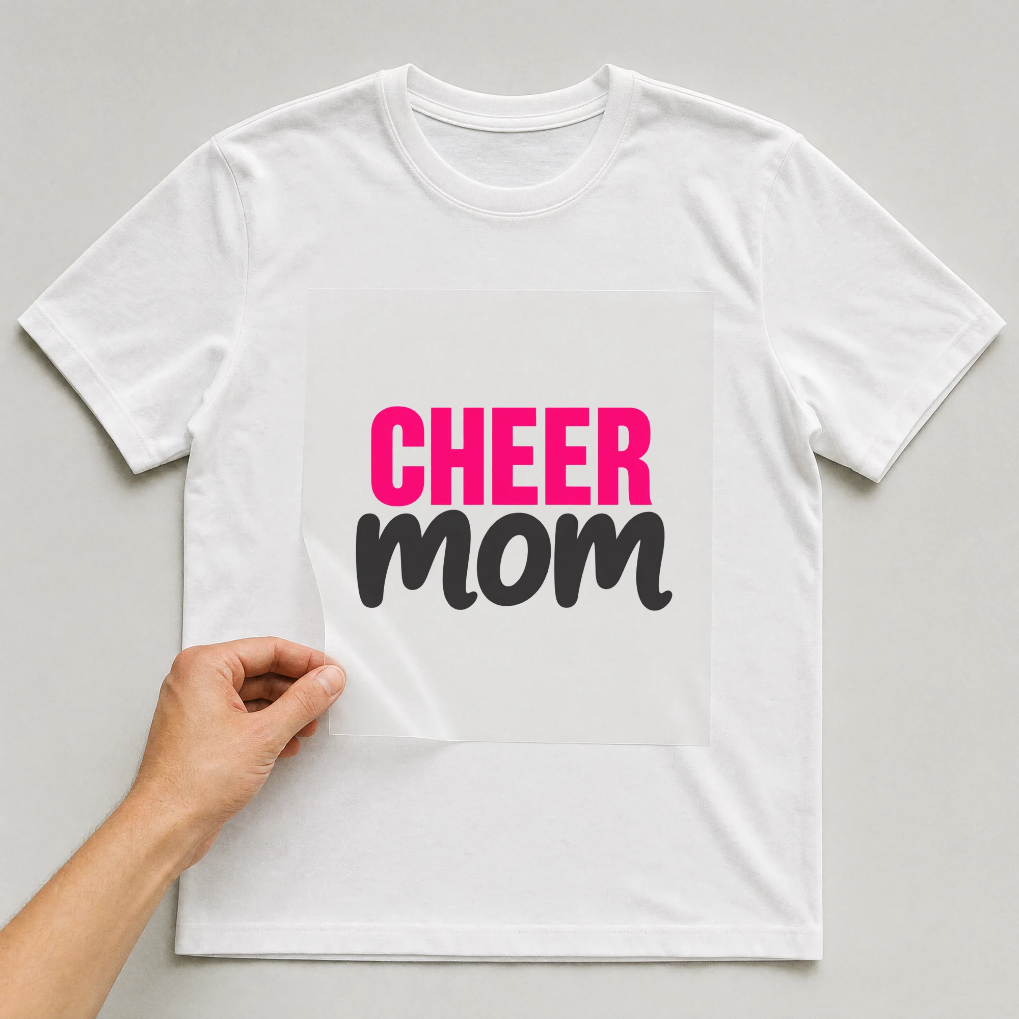 Bügelbild „CHEER mom“ auf weißem T-Shirt, Folie wird aufgelegt