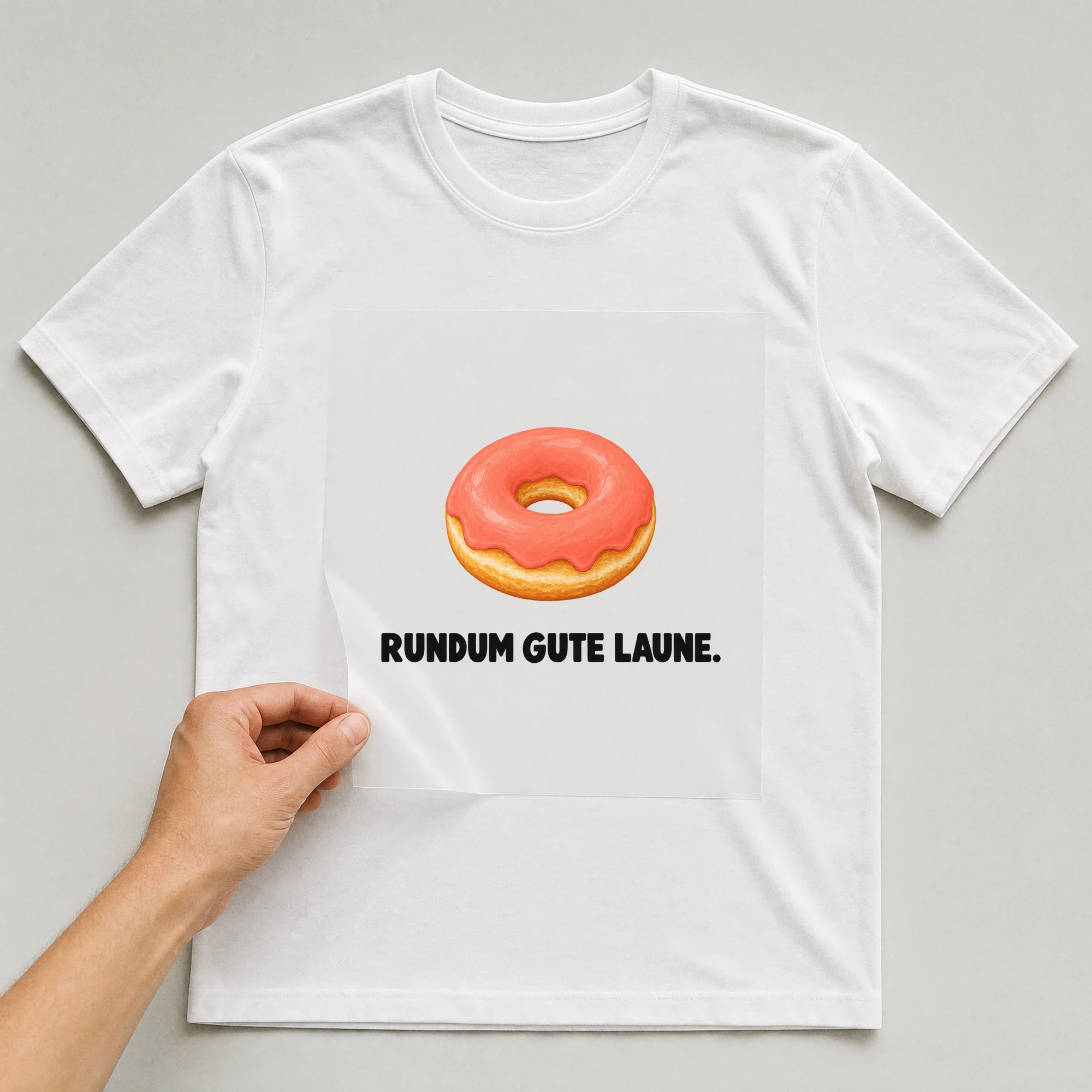 Bügelbild „RUNDUM GUTE LAUNE.“ auf weißem T-Shirt, Folie wird aufgelegt