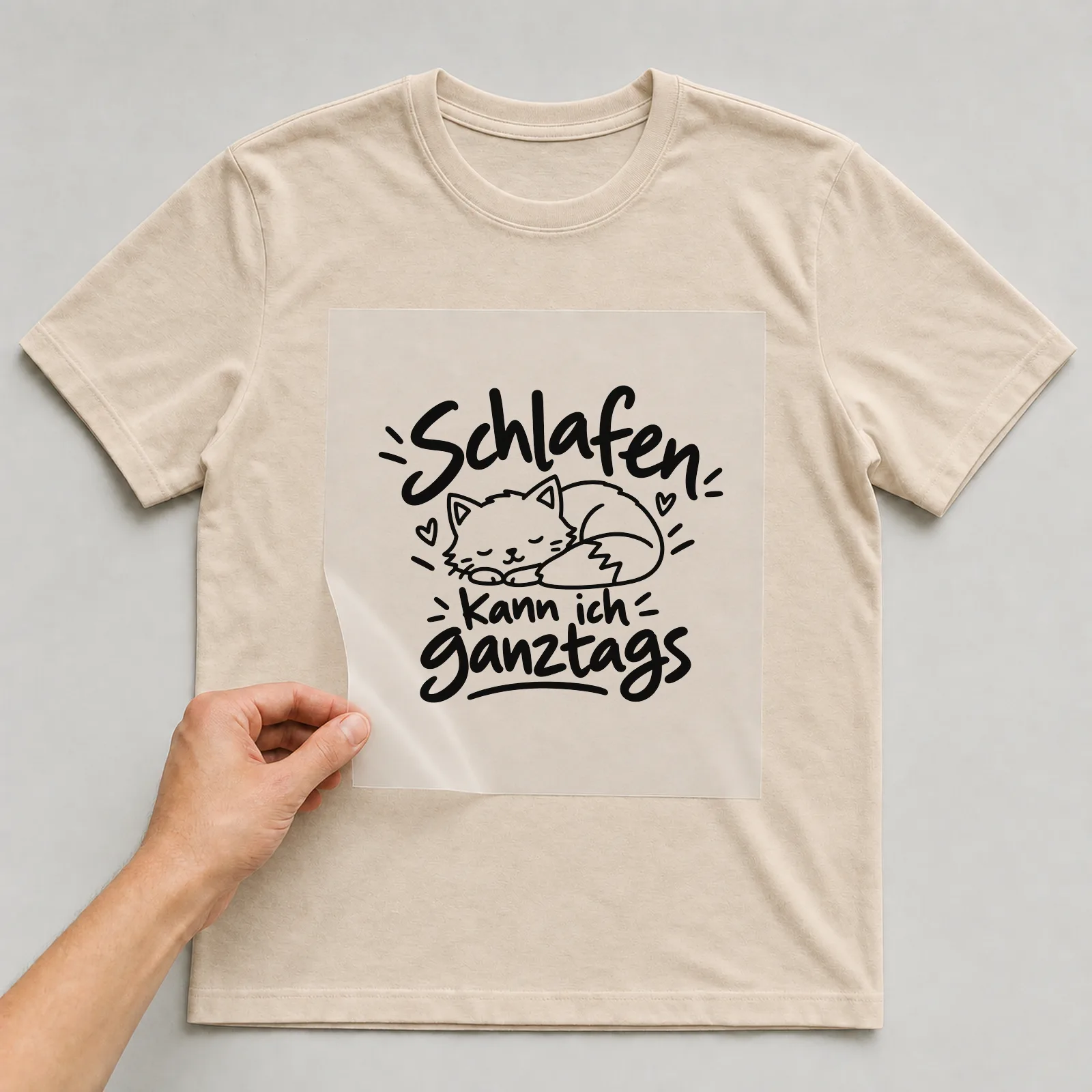 Bügelbild „Schlafen kann ich ganztags“ auf beigem T-Shirt, Folie wird aufgelegt