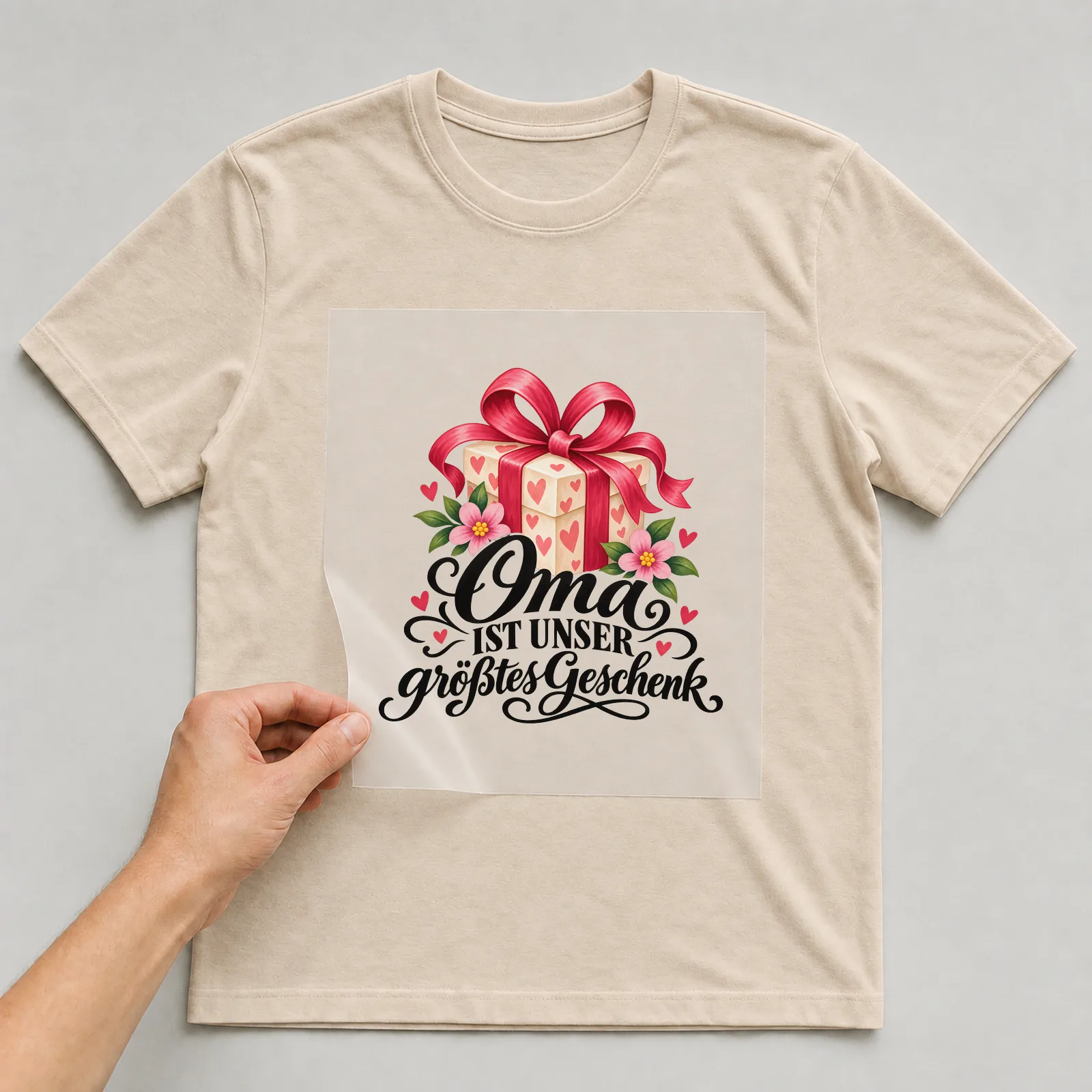 Bügelbild „Oma ist unser größtes Geschenk“ auf beigem T-Shirt, Folie wird aufgelegt