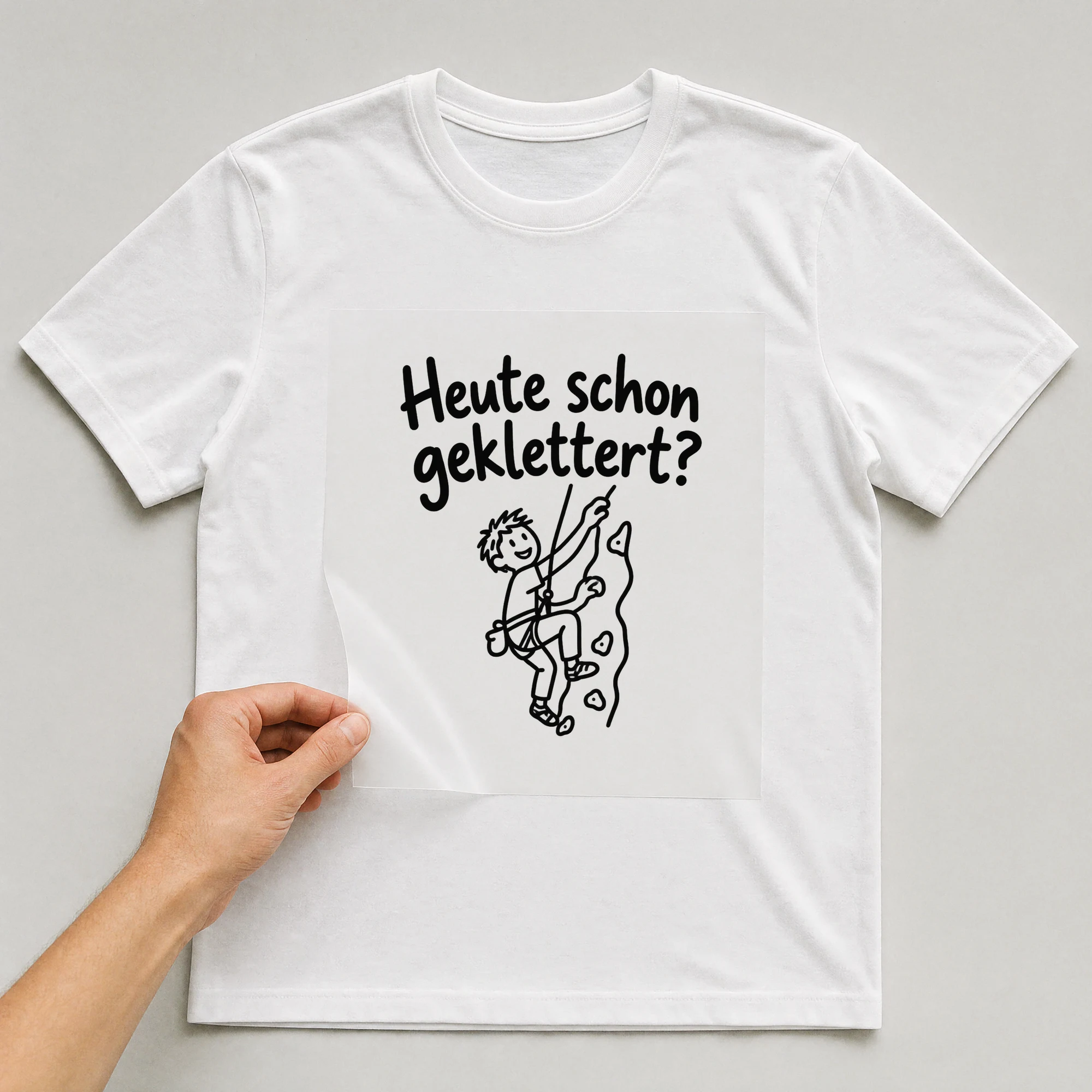 Bügelbild „Heute schon geklettert“ auf weißem T-Shirt, Folie wird aufgelegt