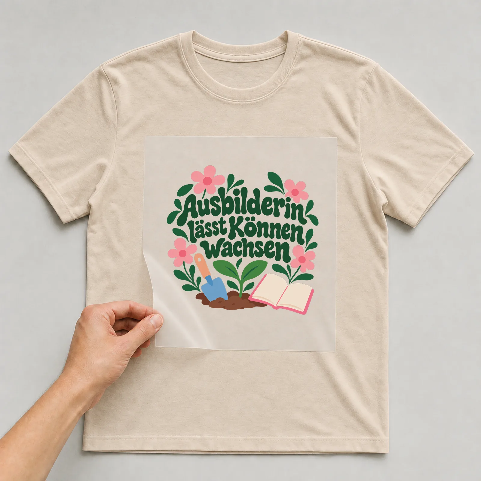 Bügelbild „Ausbilderin lässt Können wachsen“ auf beigem T-Shirt, Folie wird aufgelegt