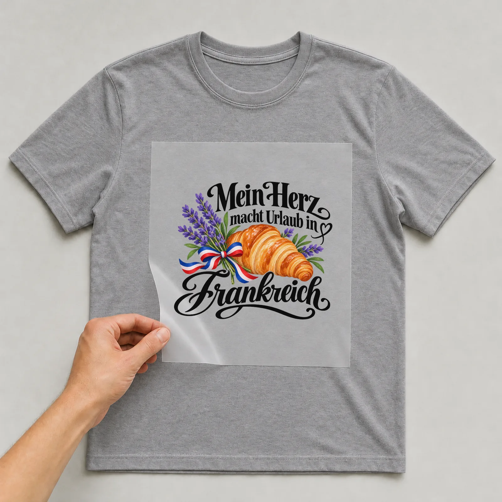 Bügelbild „Mein Herz macht Urlaub in Frankreich“ auf grauem T-Shirt, Folie wird aufgelegt