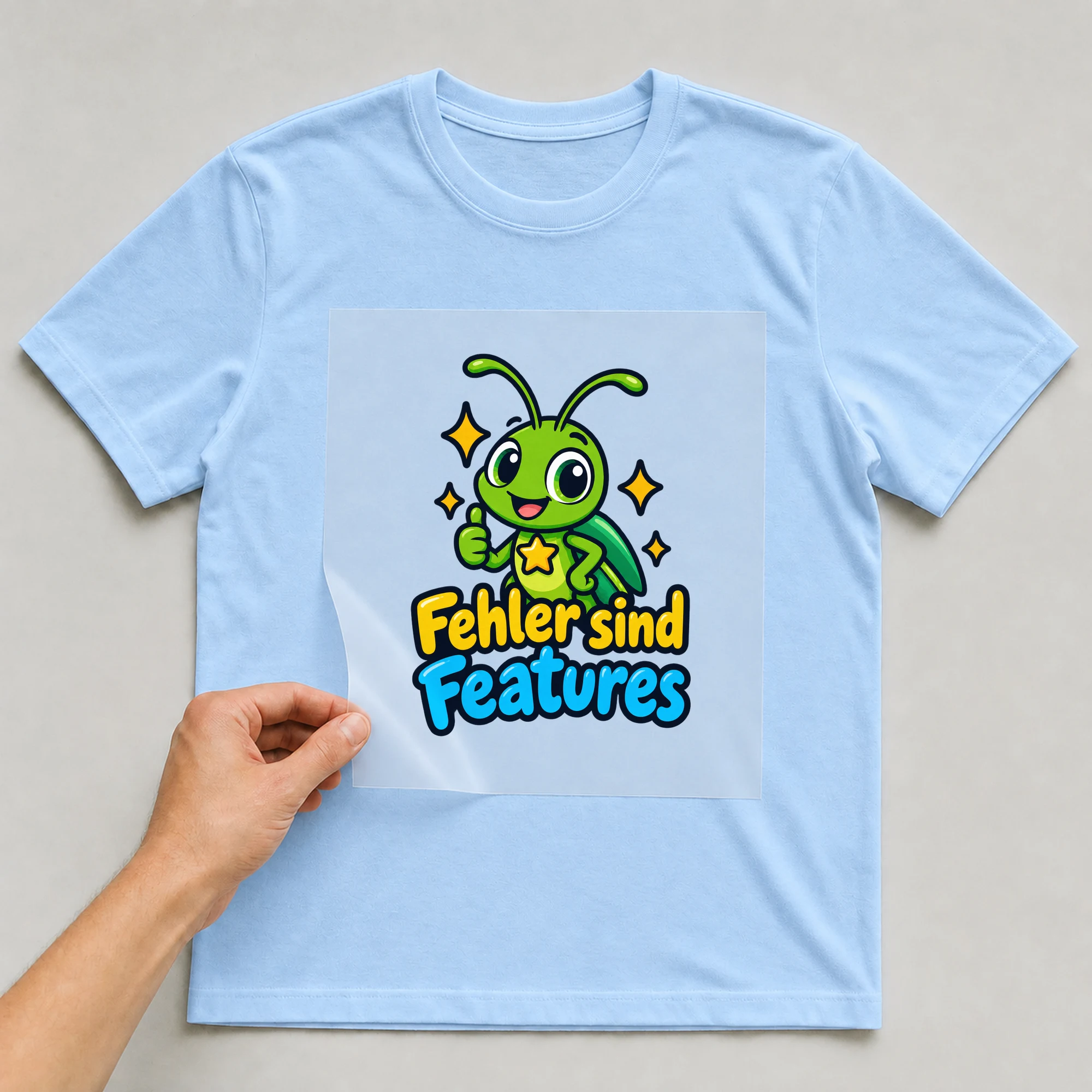 Bügelbild „Fehler sind Features“ auf babyblauem T-Shirt, Folie wird aufgelegt