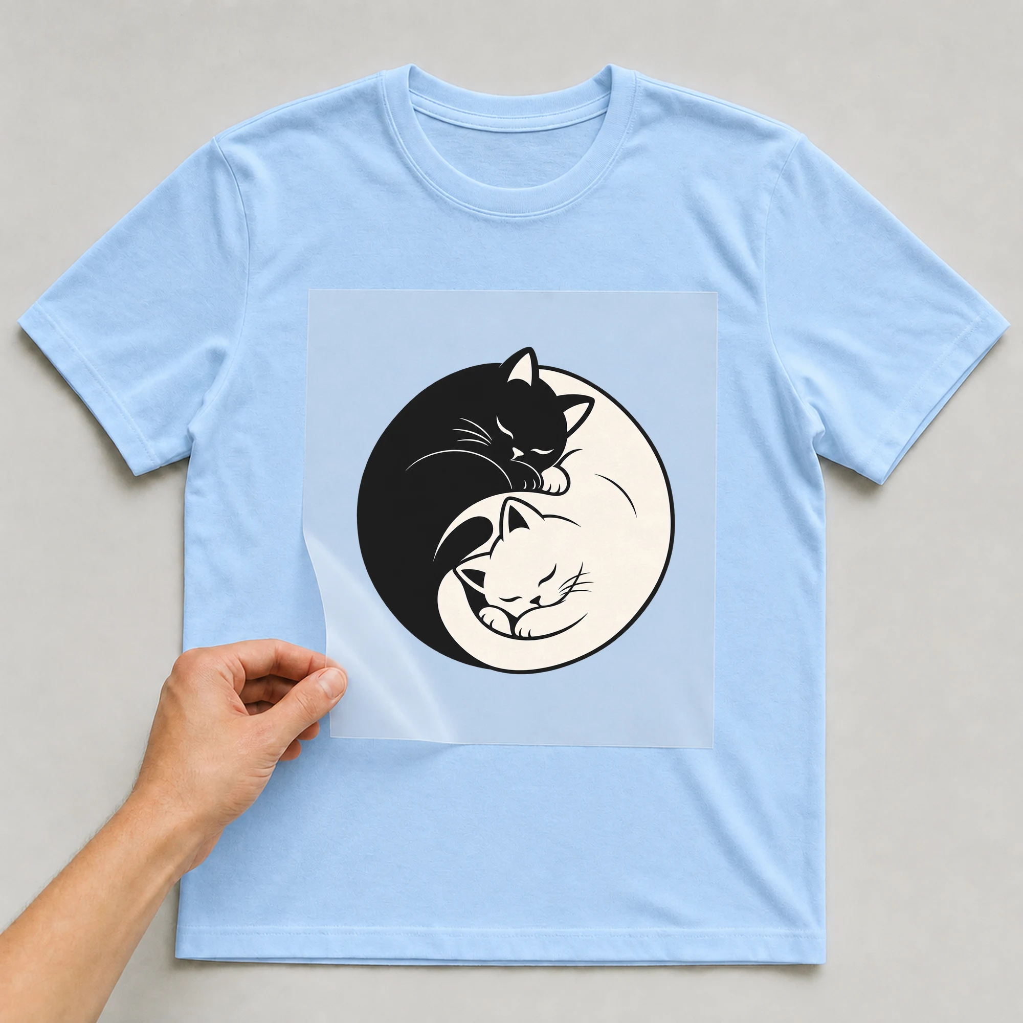 Bügelbild „Yin Yang Katze“ auf babyblauem T-Shirt, Folie wird aufgelegt