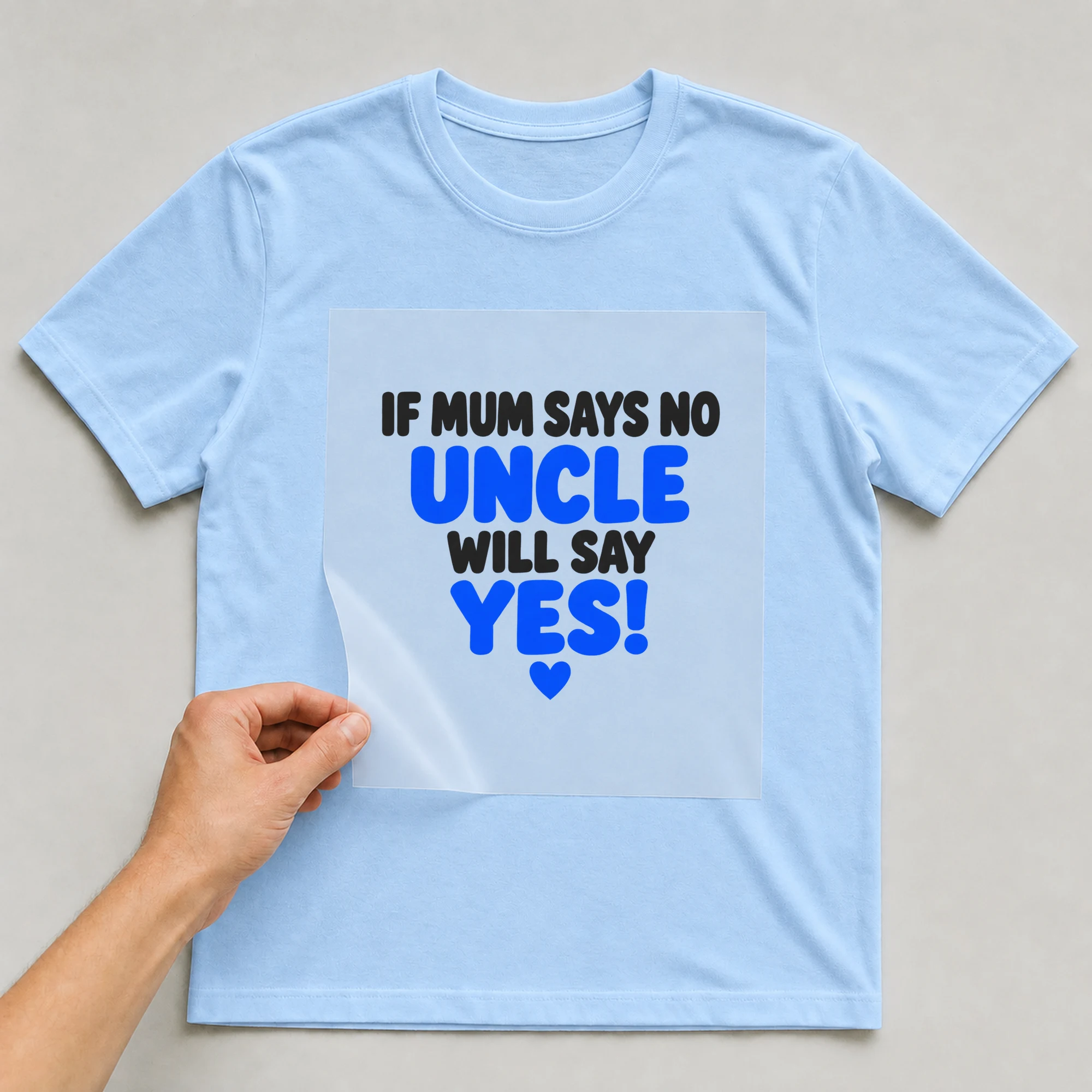 Bügelbild „If Mum Says No Uncle Will Say Yes!“ auf babyblauem T-Shirt, Folie wird aufgelegt