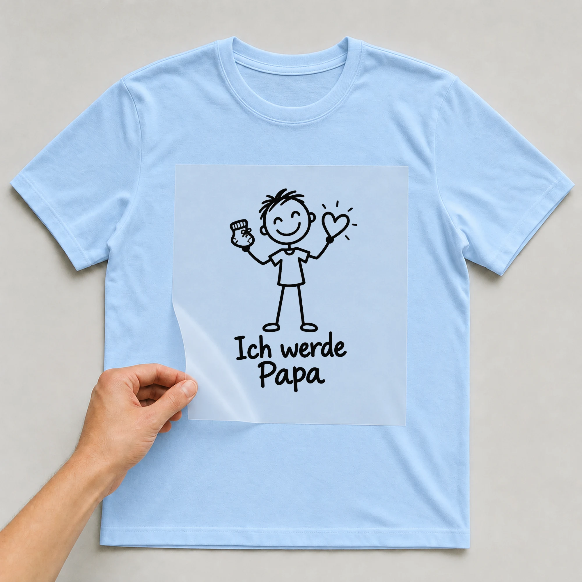 Bügelbild „Ich werde Papa“ auf babyblauem T-Shirt, Folie wird aufgelegt