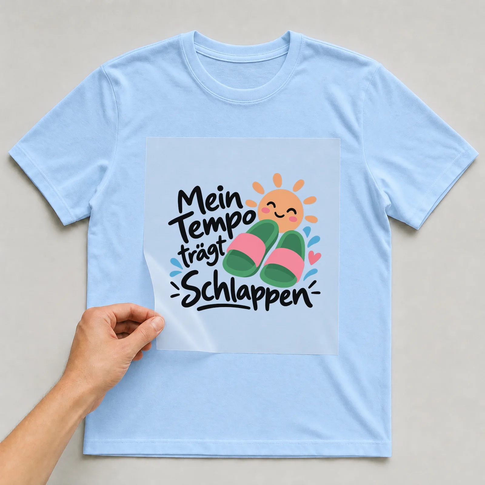 Bügelbild „Mein Tempo trägt Schlappen“ auf hellblauem T-Shirt, Folie wird aufgelegt