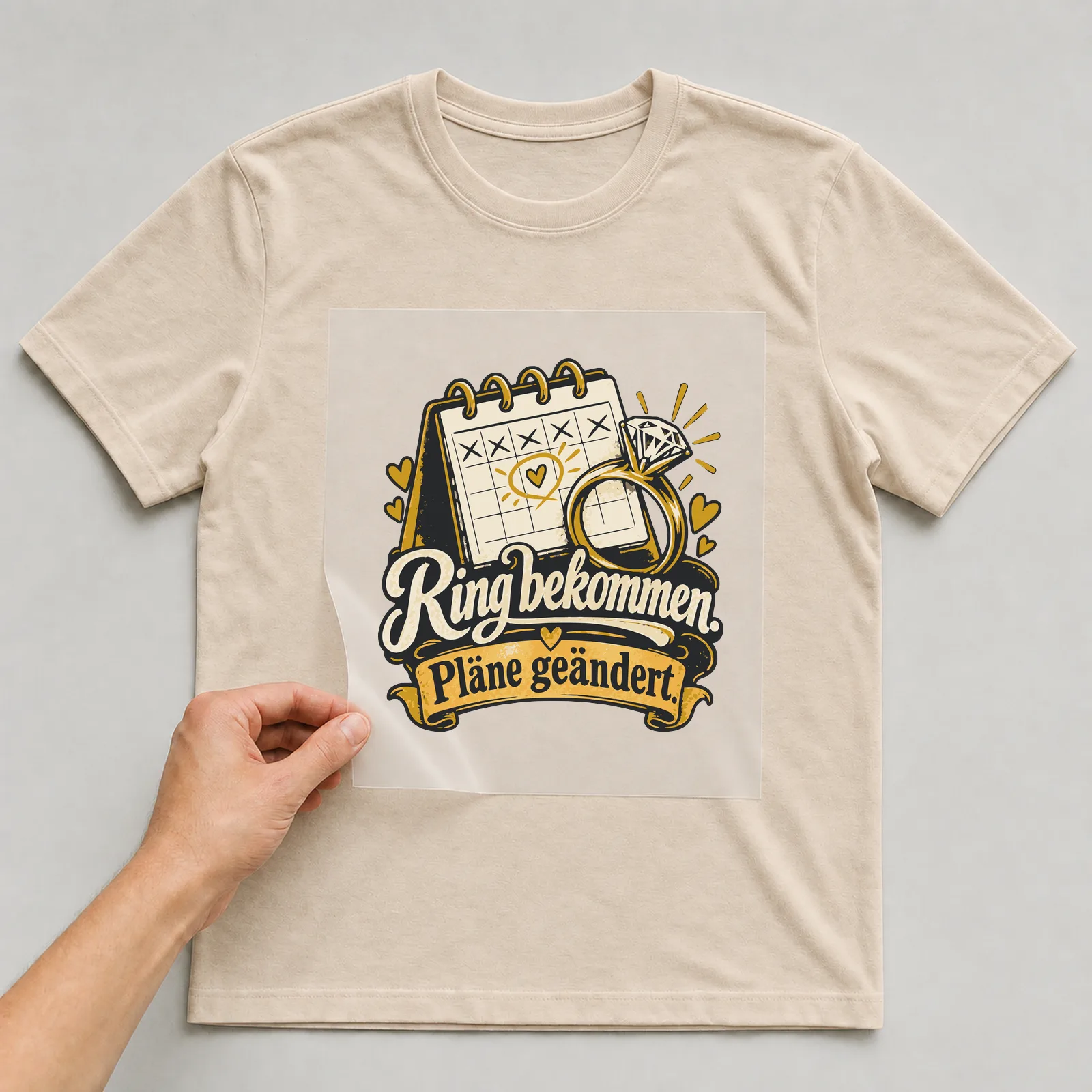 Bügelbild Ring bekommen. Pläne geändert. auf beigem T-Shirt, Folie wird aufgelegt