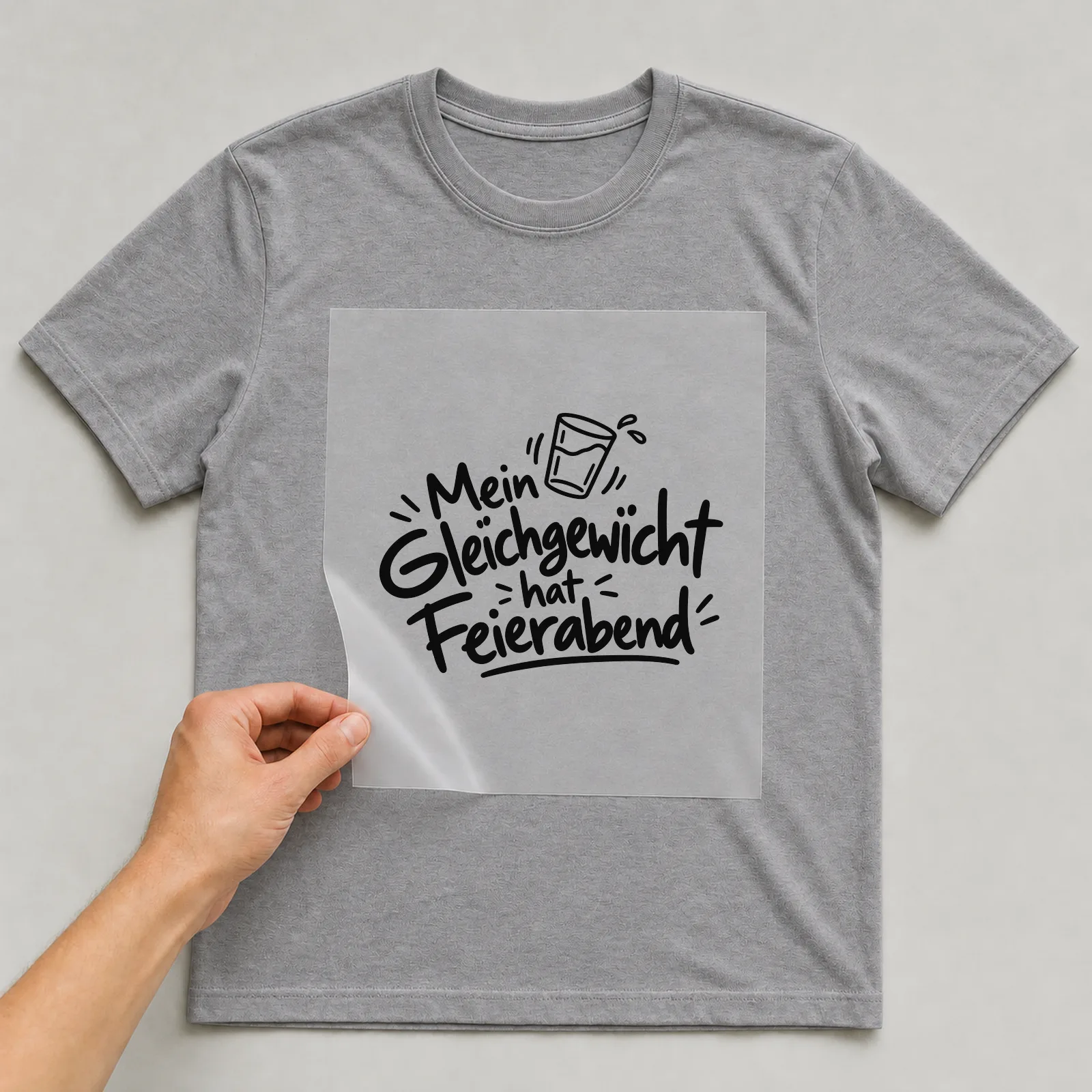 Bügelbild „Mein Gleichgewicht hat Feierabend“ auf grauem T-Shirt, Folie wird aufgelegt