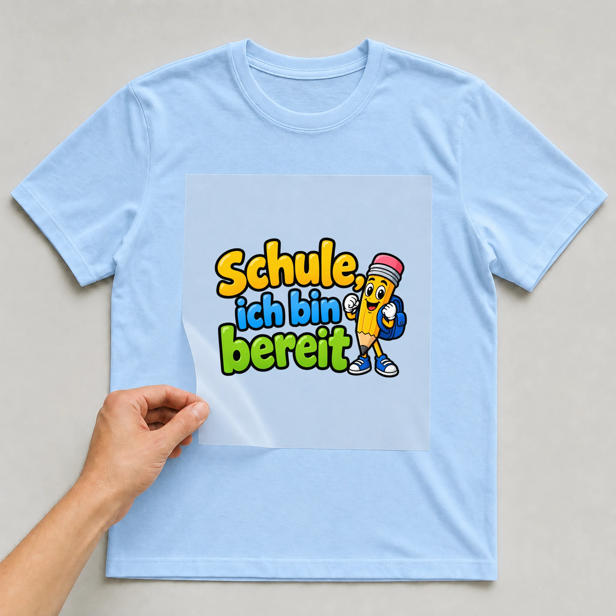 Bügelbild „Schule ich bin bereit“ auf babyblauem T-Shirt, Folie wird aufgelegt