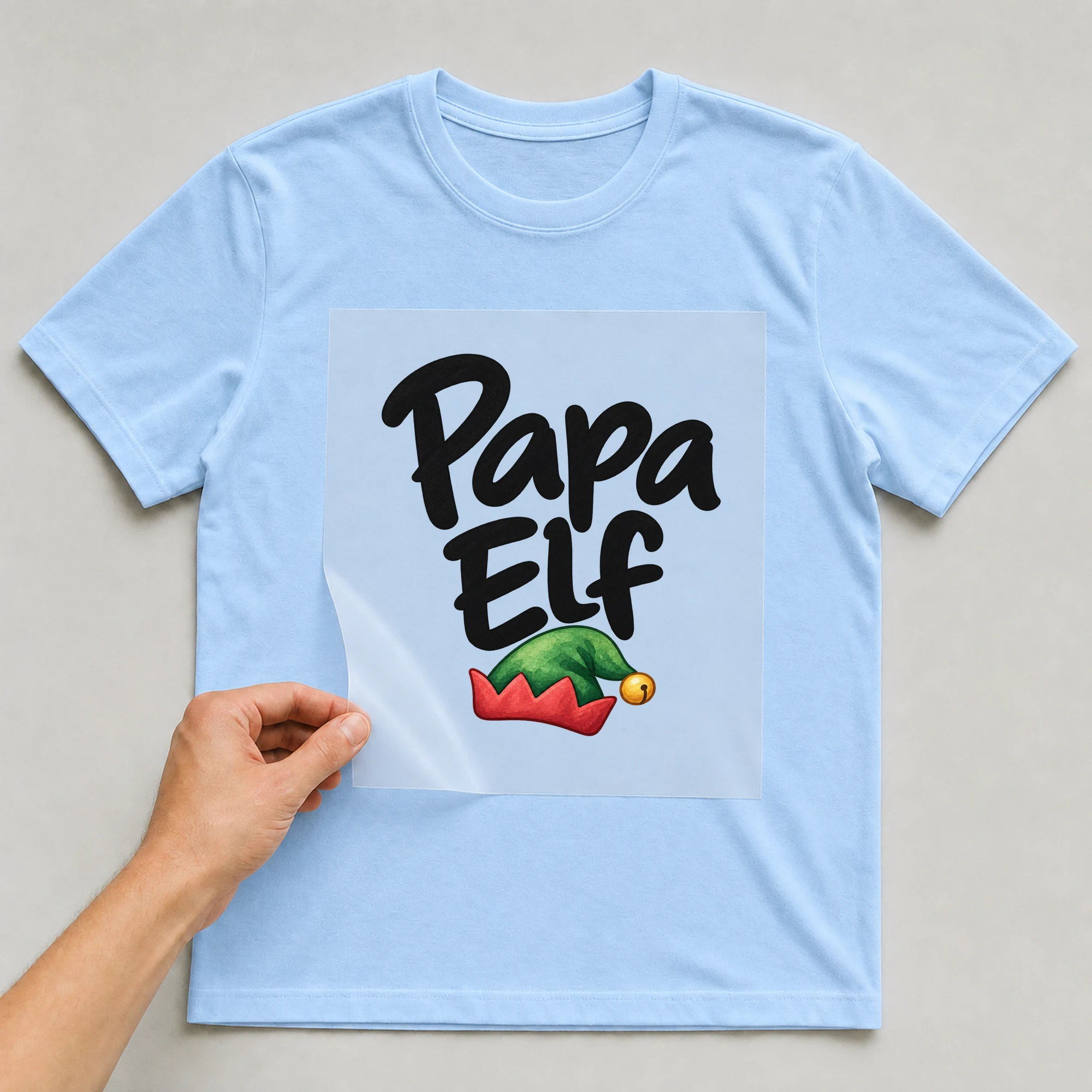 Bügelbild „Papa Elf“ auf babyblauem T-Shirt, Folie wird aufgelegt