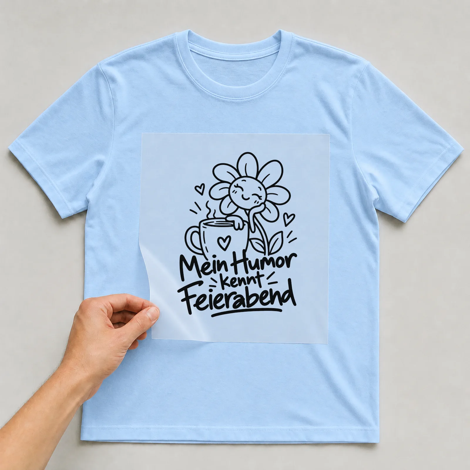 Bügelbild „Mein Humor kennt Feierabend“ auf hellblauem T-Shirt, Folie wird aufgelegt