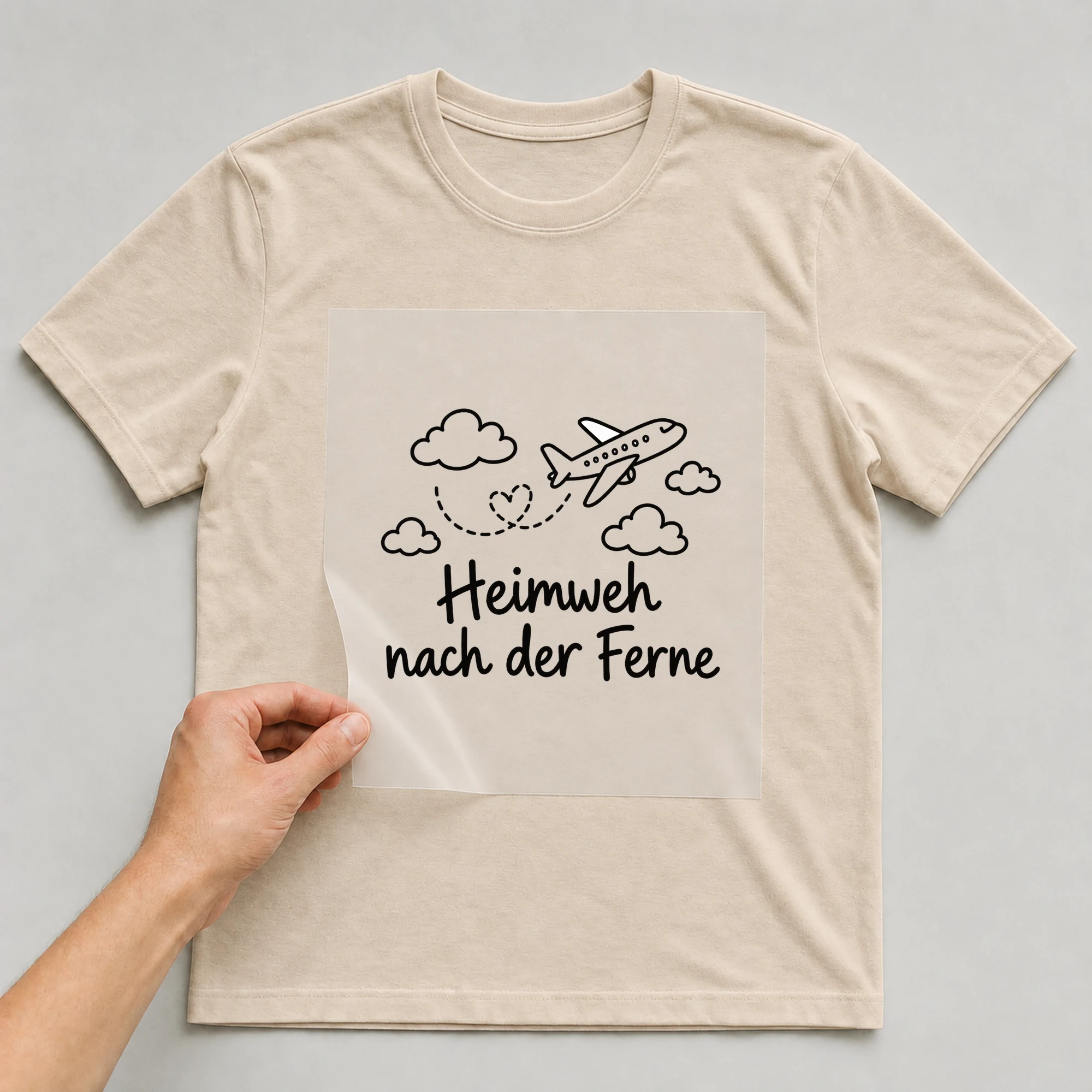 Bügelbild „Heimweh nach der Ferne“ auf beigem T-Shirt, Folie wird aufgelegt