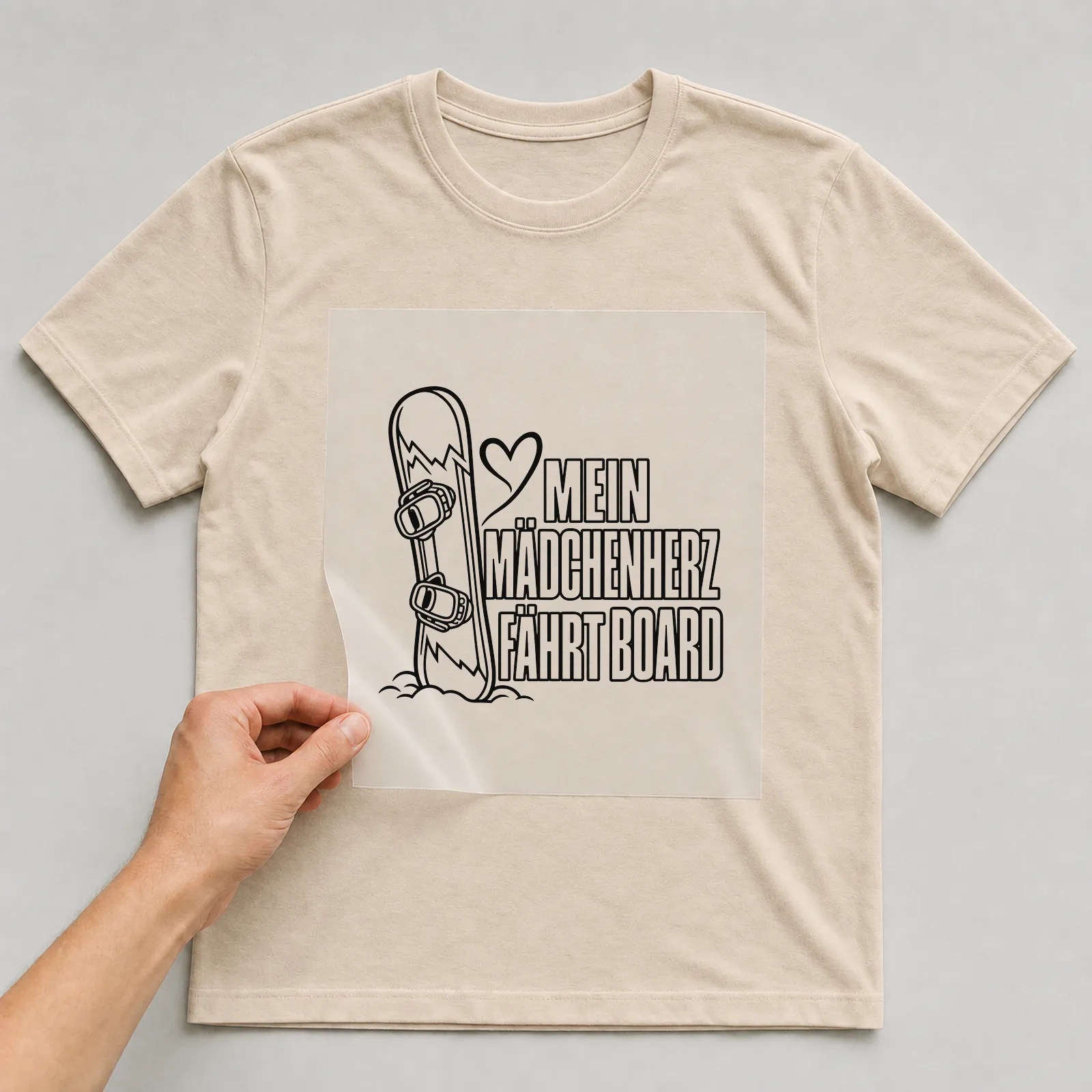Bügelbild „Mein Mädchenherz fährt Board“ auf beigem T-Shirt, Folie wird aufgelegt