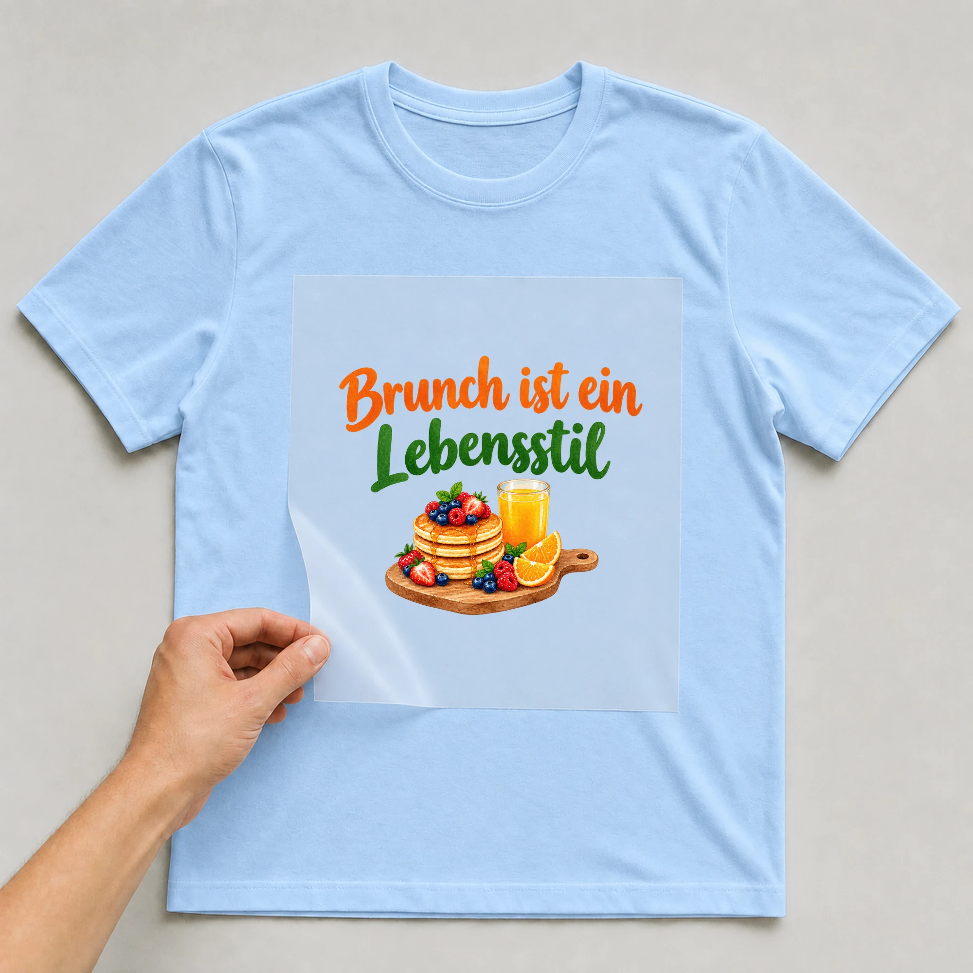 Bügelbild „Brunch ist ein Lebensstil“ auf babyblauem T-Shirt, Folie wird aufgelegt