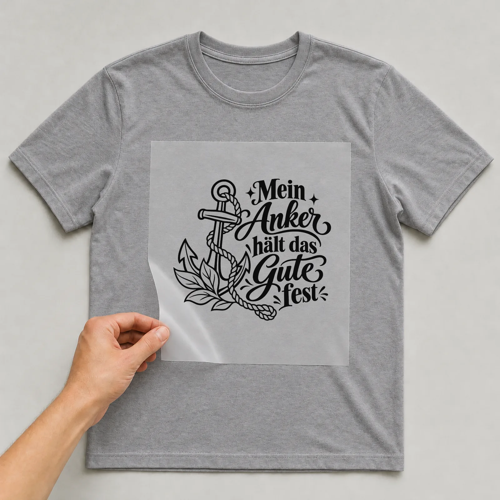 Bügelbild „Mein Anker hält das Gute fest“ auf grauem T-Shirt, Folie wird aufgelegt