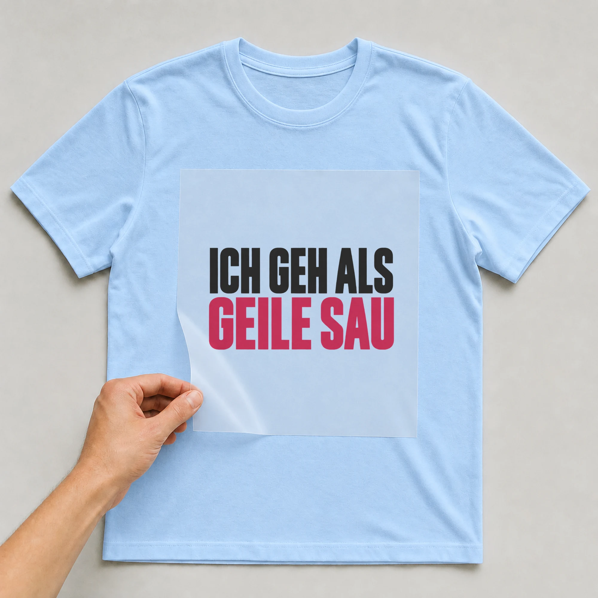 Bügelbild „Ich geh als geile Sau“ auf babyblauem T-Shirt, Folie wird aufgelegt