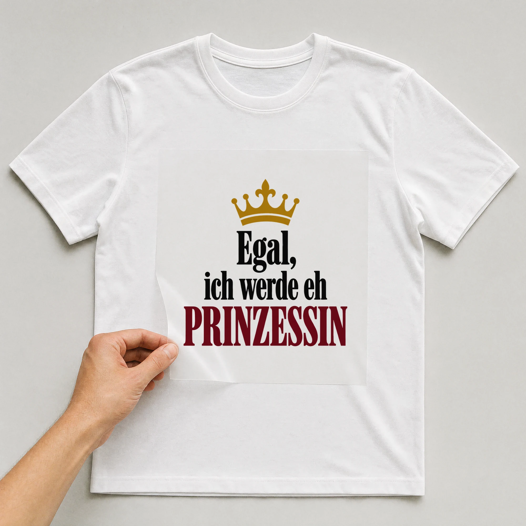 Bügelbild „Egal, ich werde eh Prinzessin“ auf weißem T-Shirt, Folie wird aufgelegt