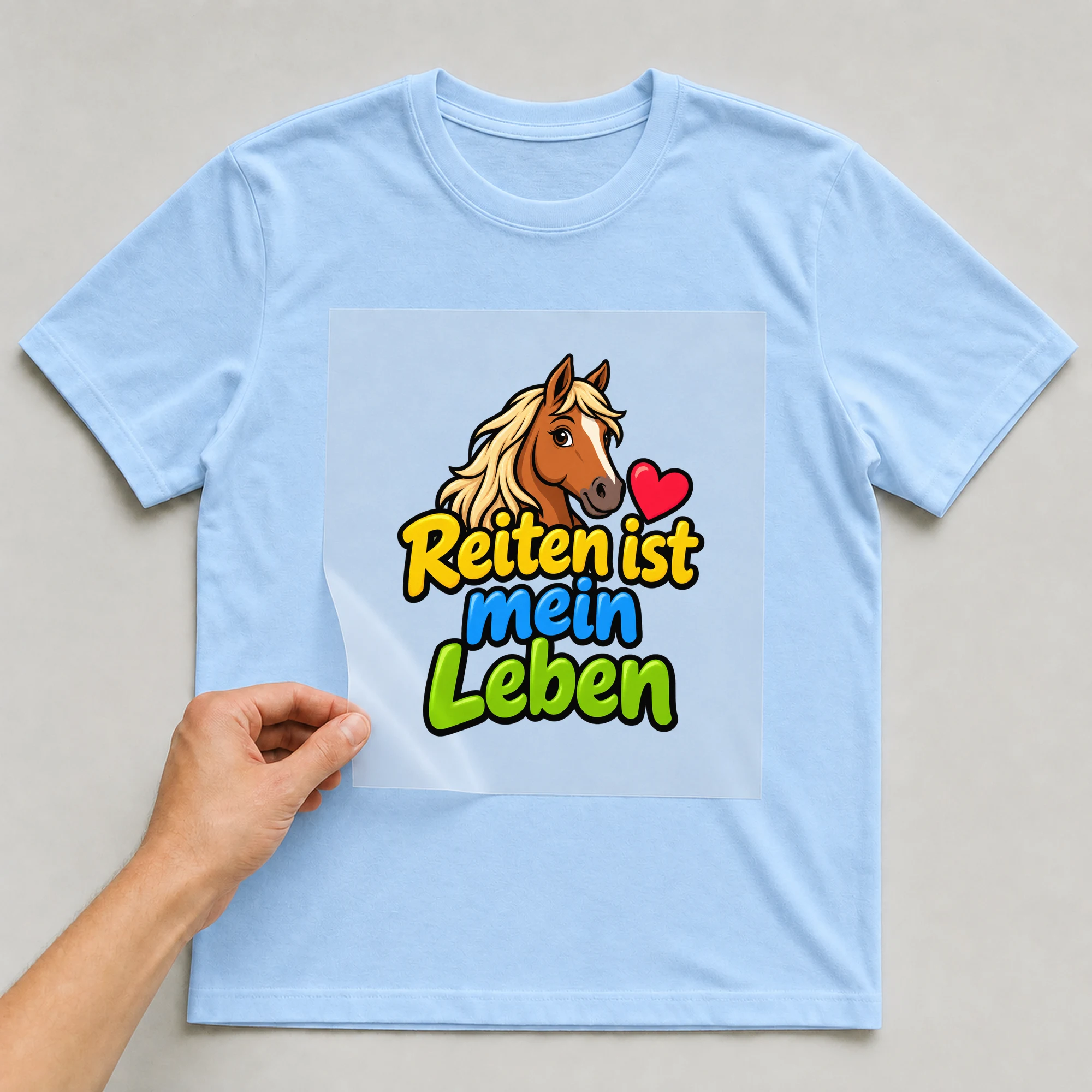 Bügelbild „Reiten ist mein Leben“ auf babyblauem T-Shirt, Folie wird aufgelegt