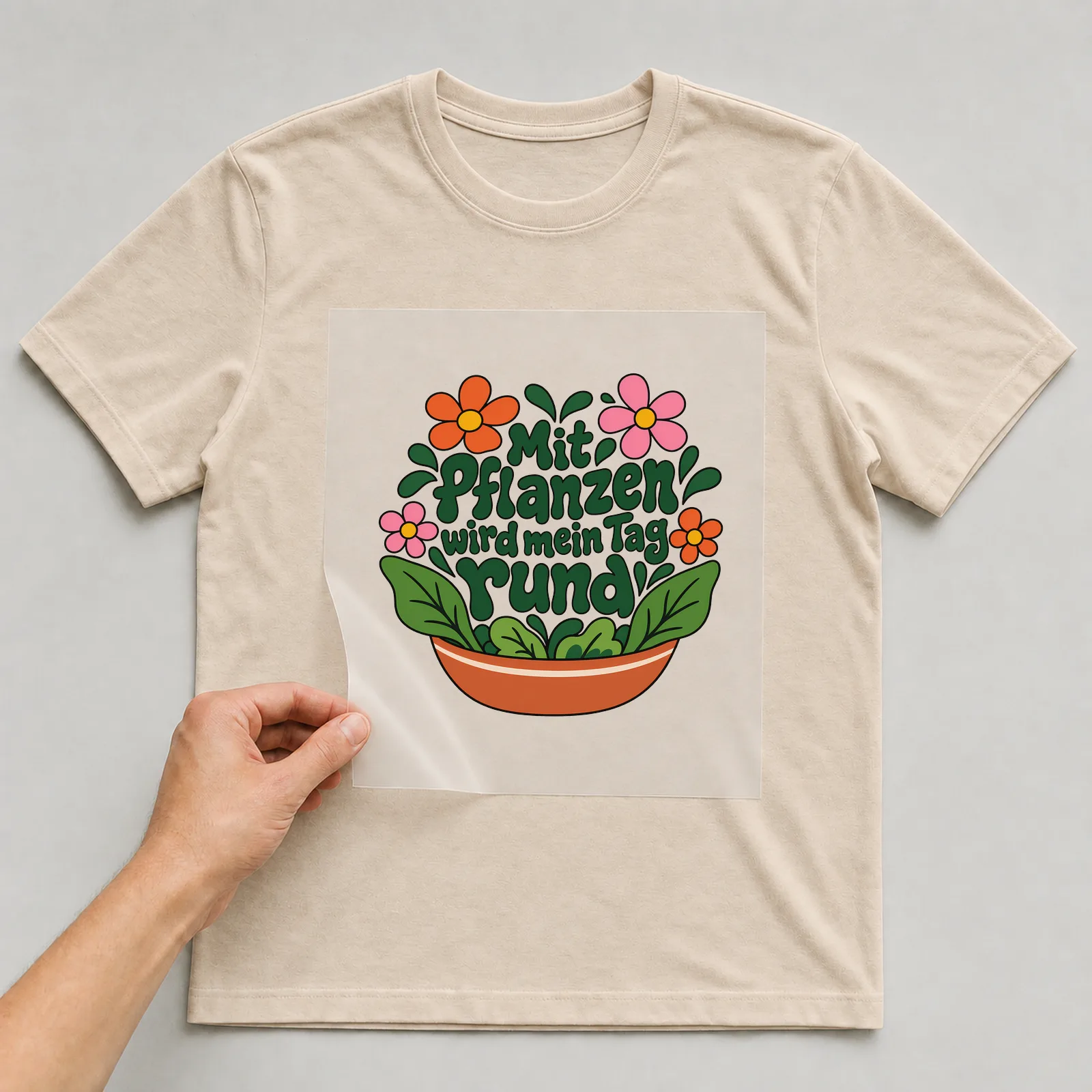 Bügelbild „Mit Pflanzen wird mein Tag rund“ auf beigem T-Shirt, Folie wird aufgelegt