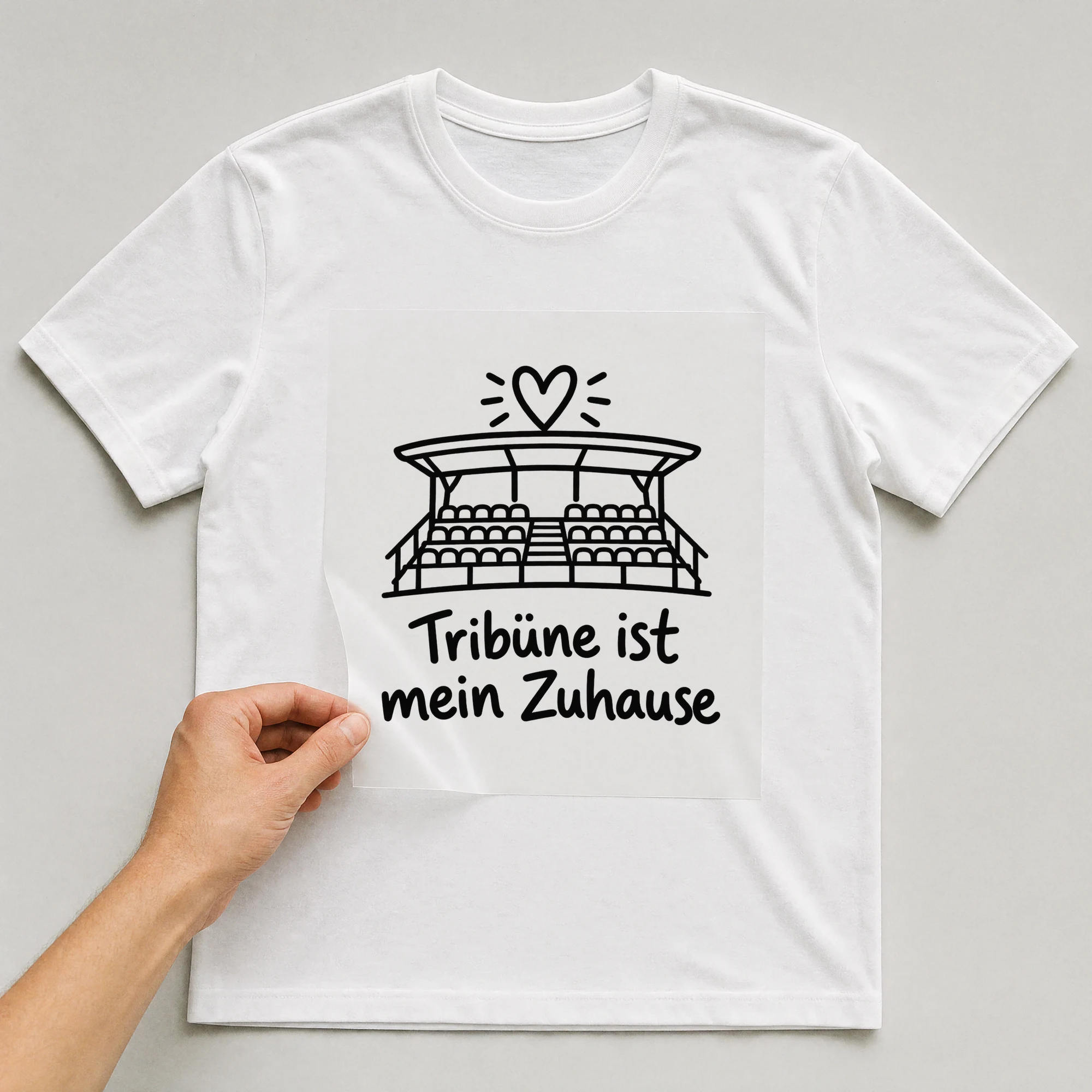 Bügelbild „Tribüne ist mein Zuhause“ auf weißem T-Shirt, Folie wird aufgelegt