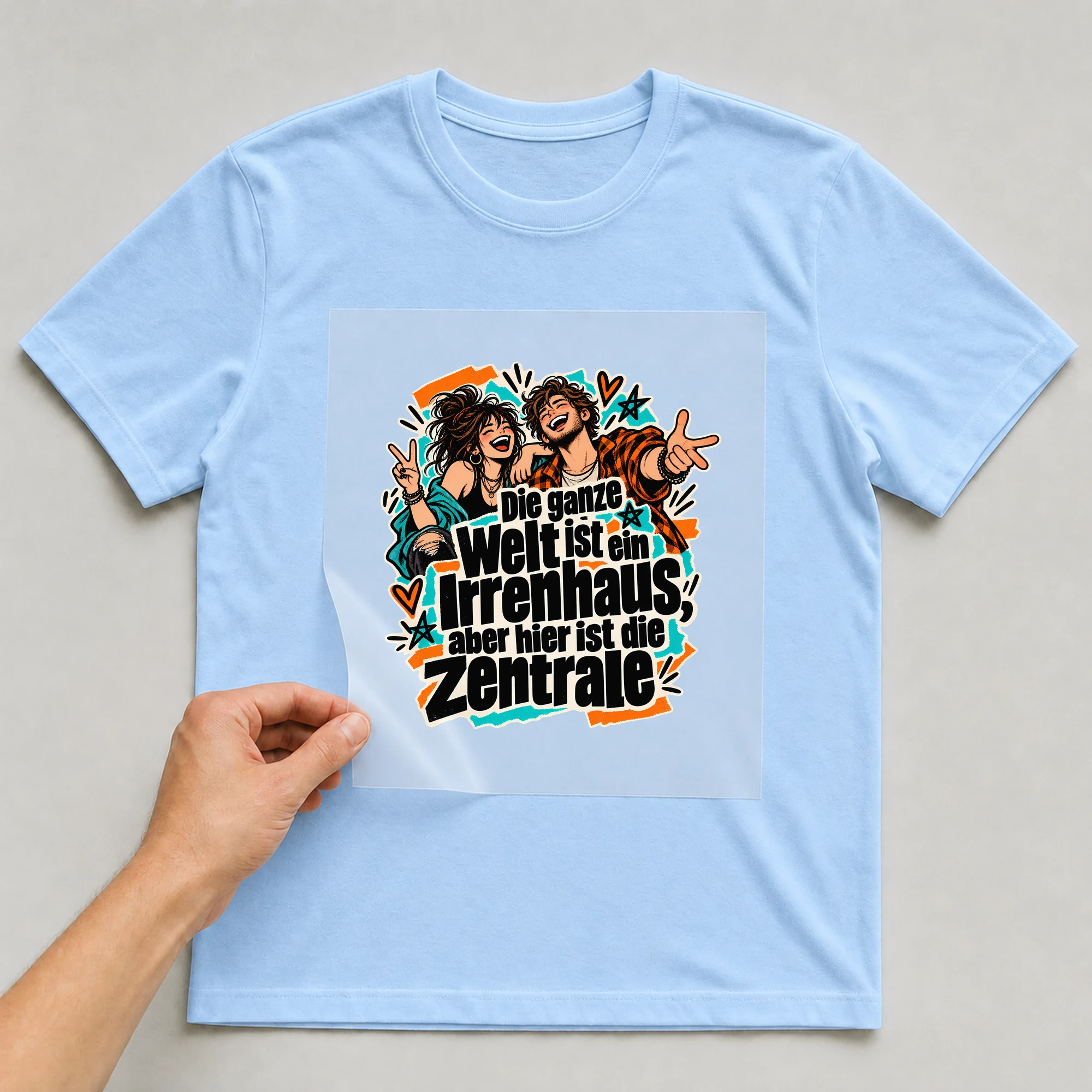 Bügelbild „Die ganze Welt ist ein Irrenhaus“ auf babyblauem T-Shirt, Folie wird aufgelegt