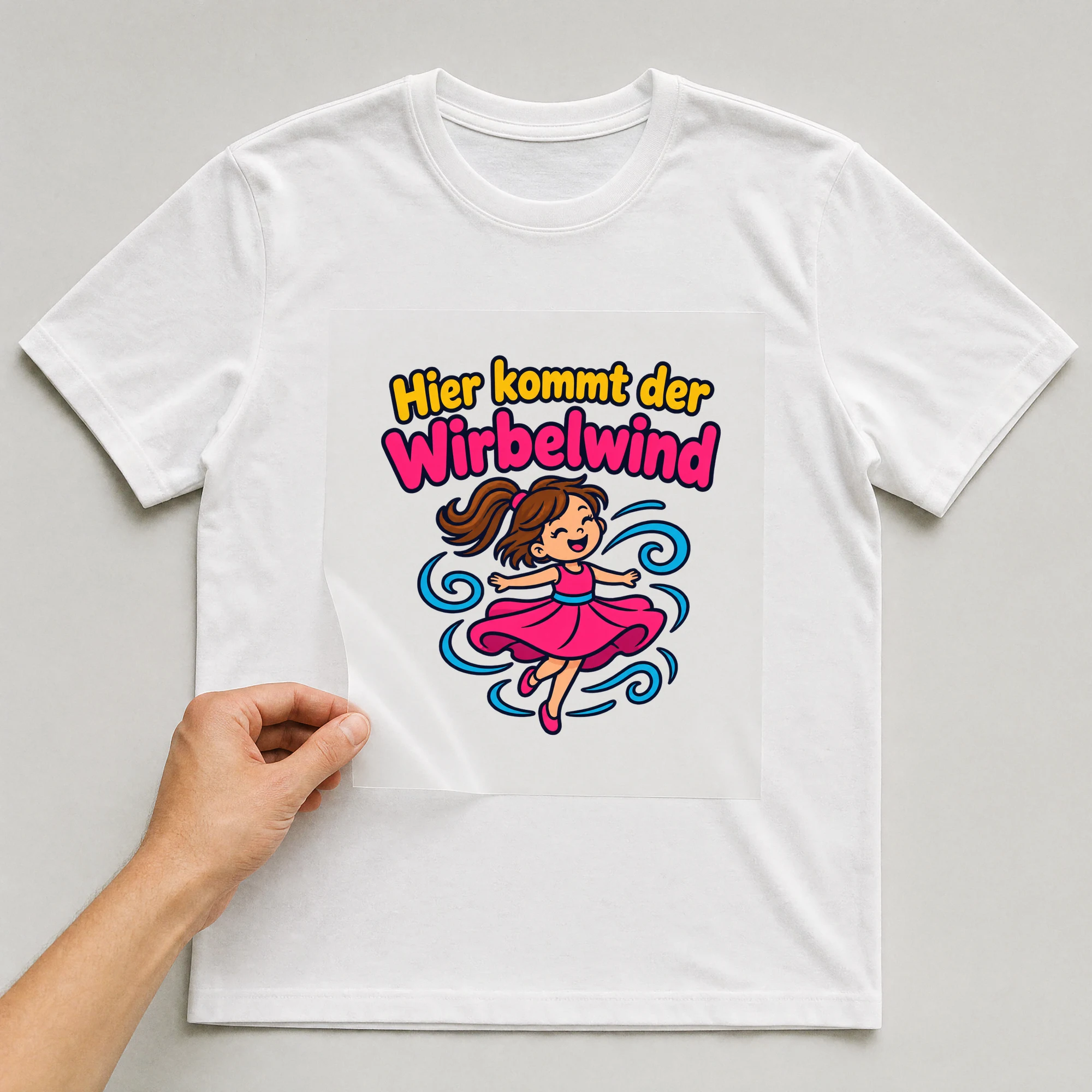 Bügelbild „Hier kommt der Wirbelwind“ auf weißem T-Shirt, Folie wird aufgelegt