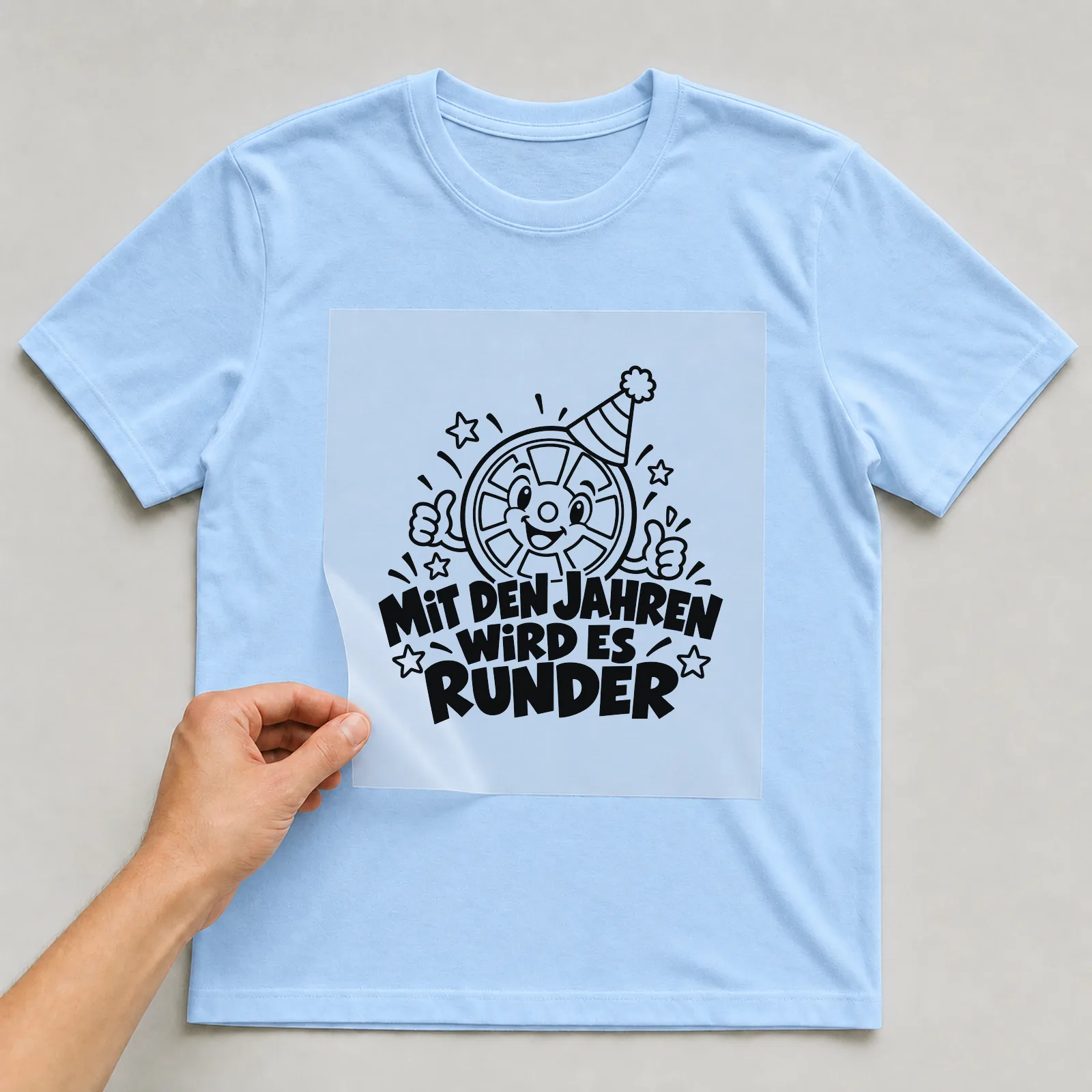 Bügelbild „Mit den Jahren wird es runder“ auf hellblauem T-Shirt, Folie wird aufgelegt