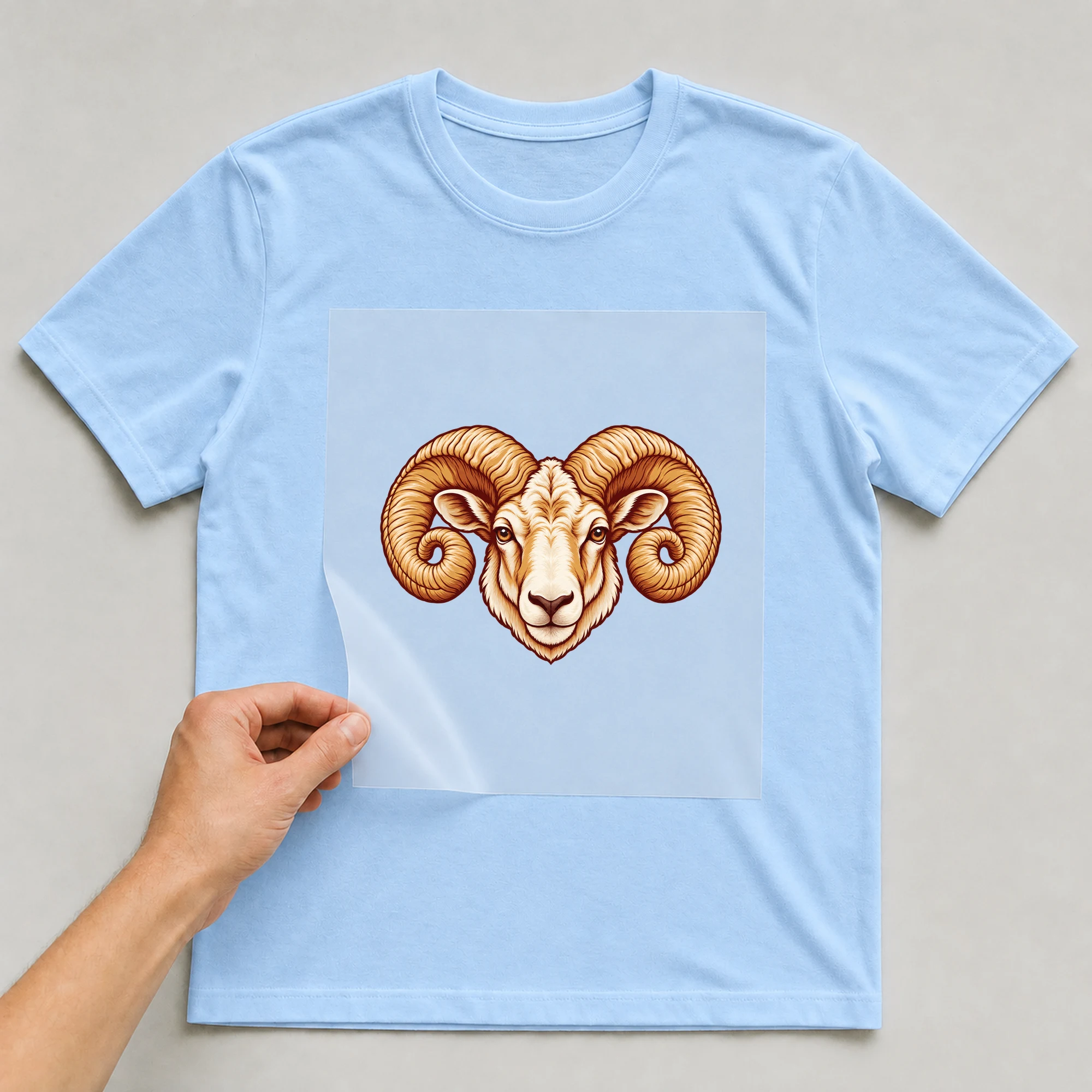 Bügelbild „Kritzel Stil Sternzeichen Widder“ auf babyblauem T-Shirt, Folie wird aufgelegt