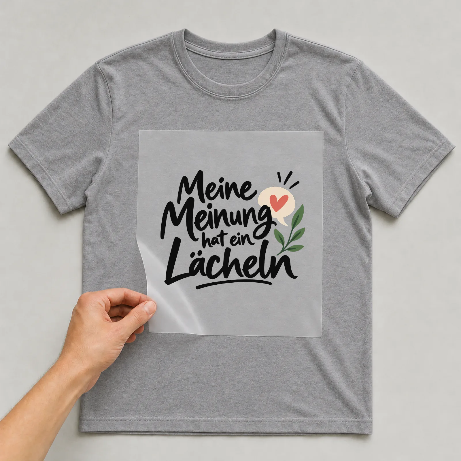 Bügelbild „Meine Meinung hat ein Lächeln“ auf grauem T-Shirt, Folie wird aufgelegt