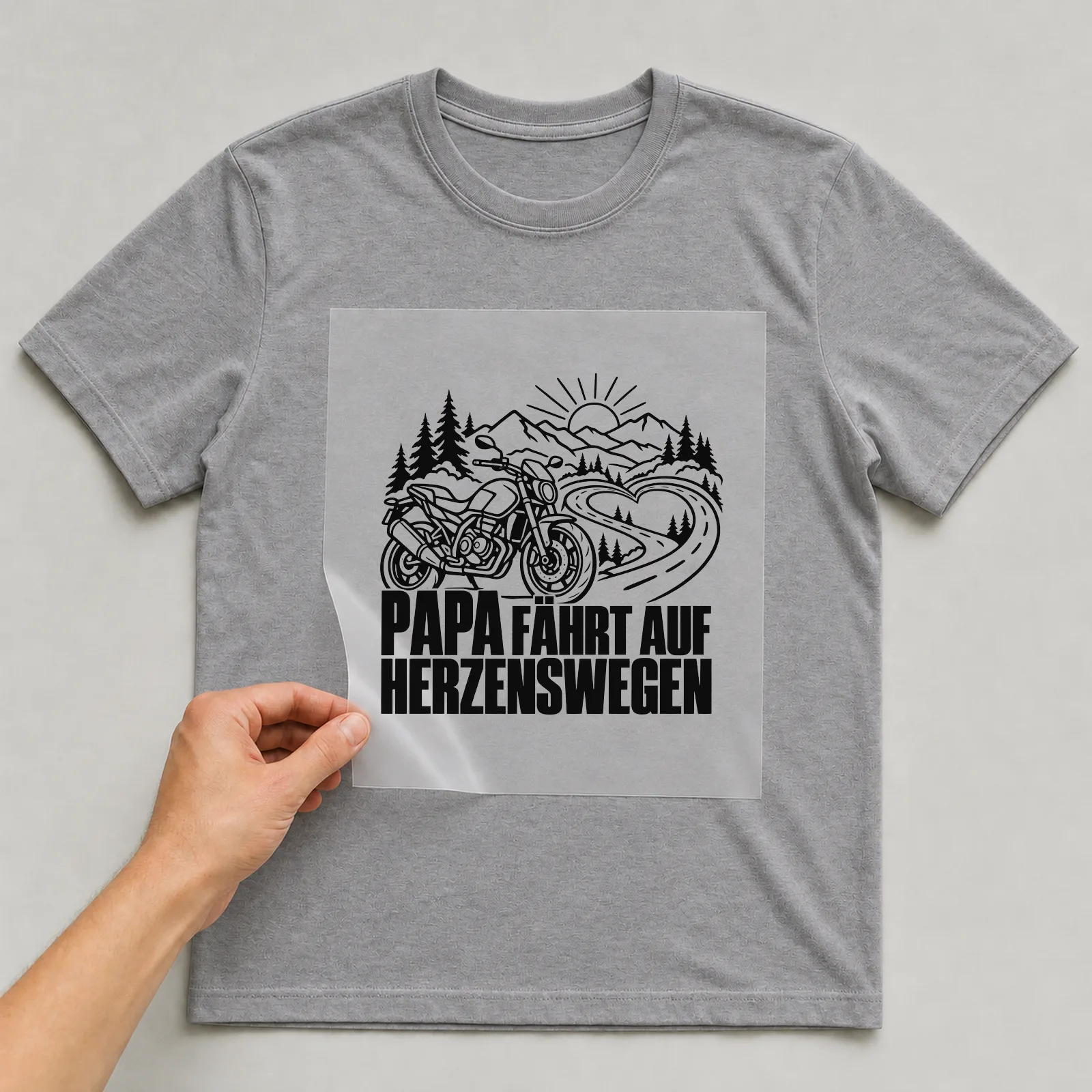 Bügelbild „Papa fährt auf Herzenswegen“ auf grauem T-Shirt, Folie wird aufgelegt
