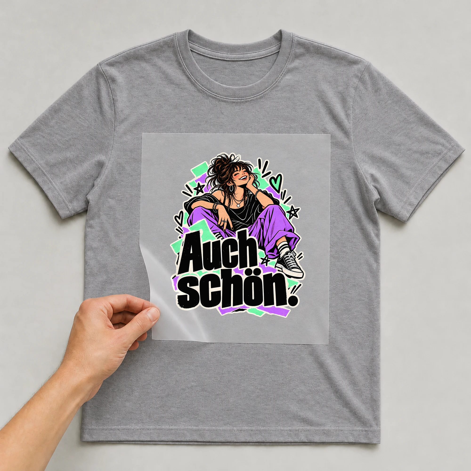 Bügelbild „Auch schön.“ auf grauem T-Shirt, Folie wird aufgelegt