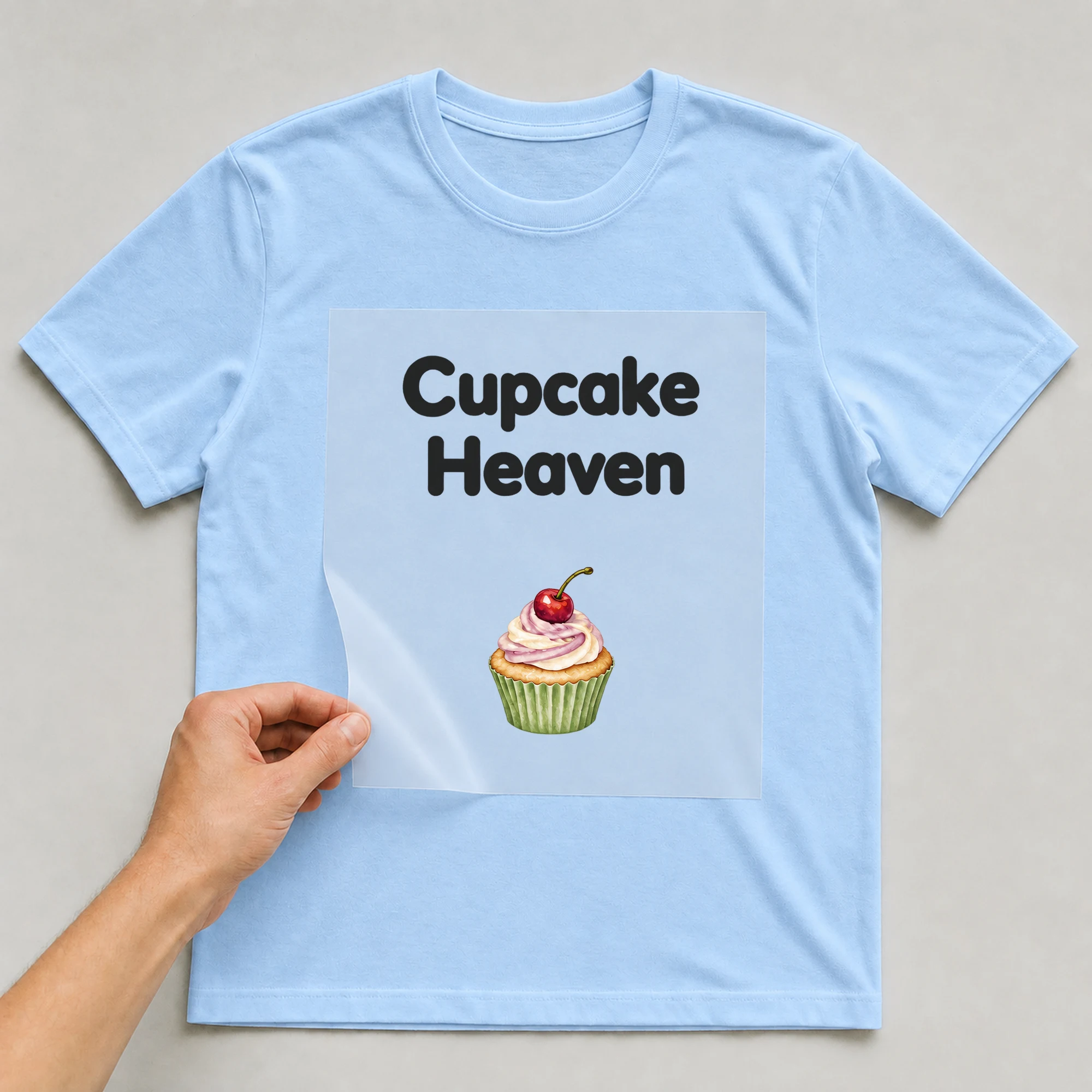 Bügelbild „Cupcake Heaven“ auf babyblauem T-Shirt, Folie wird aufgelegt