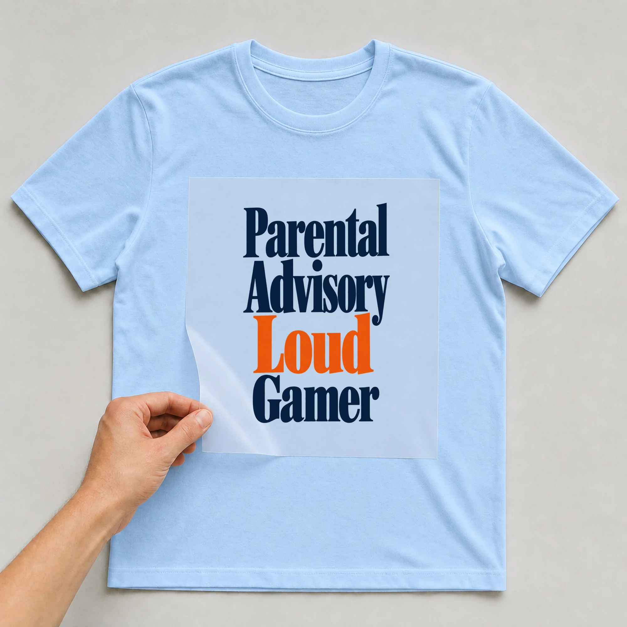 Bügelbild „Parental Advisory Loud Gamer“ auf babyblauem T-Shirt, Folie wird aufgelegt