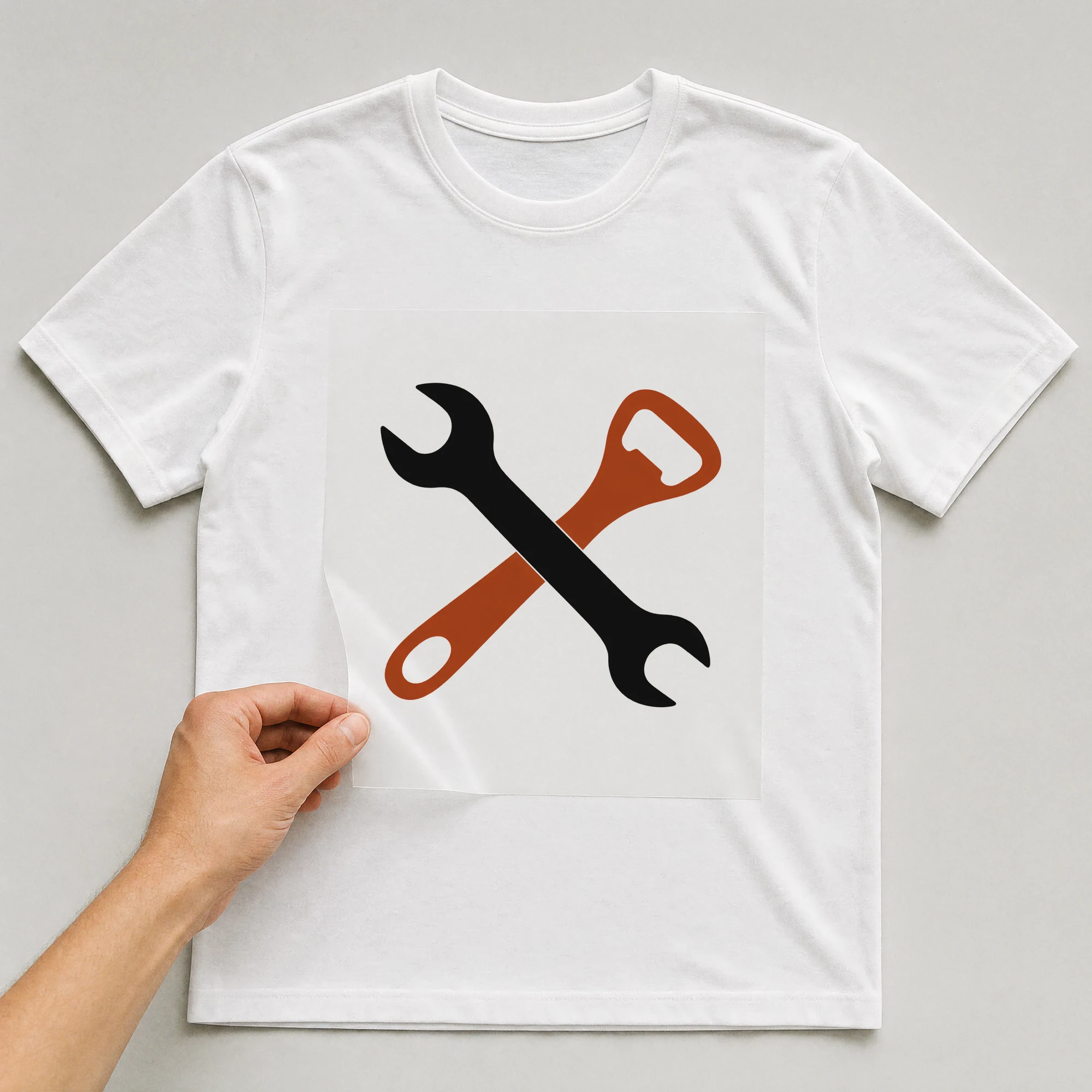 Bügelbild „Werkzeug Bieröffner“ auf weißem T-Shirt, Folie wird aufgelegt