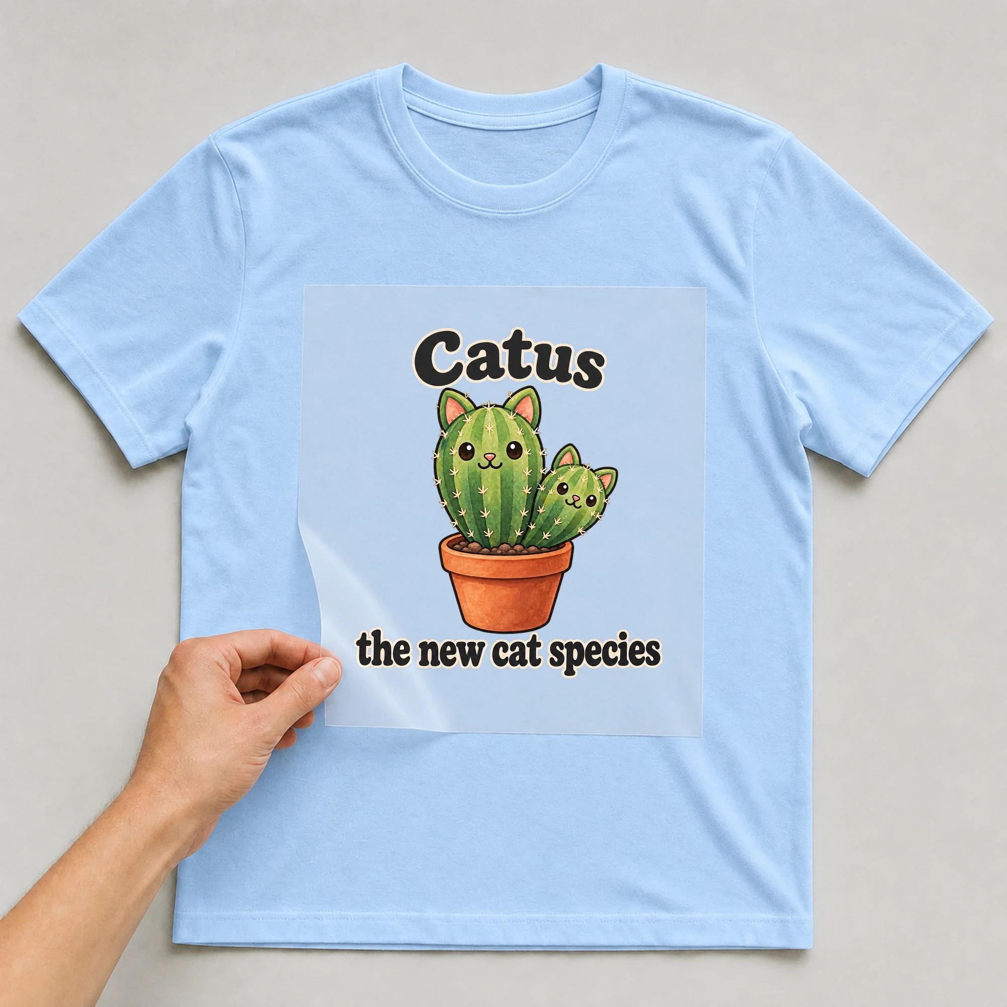 Bügelbild „Catus the new cat species“ auf babyblauem T-Shirt, Folie wird aufgelegt