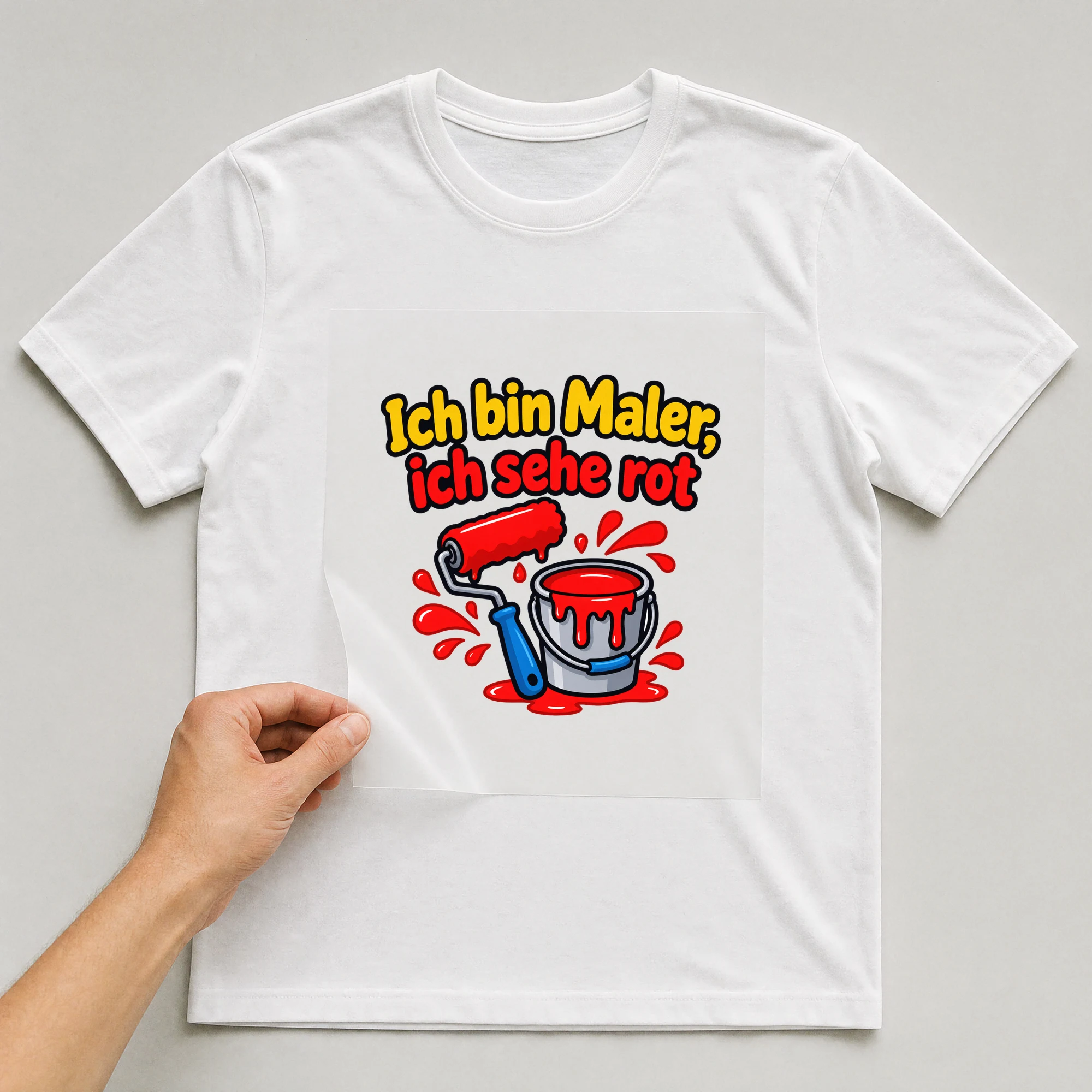 Bügelbild „Ich bin Maler, ich sehe rot“ auf weißem T-Shirt, Folie wird aufgelegt