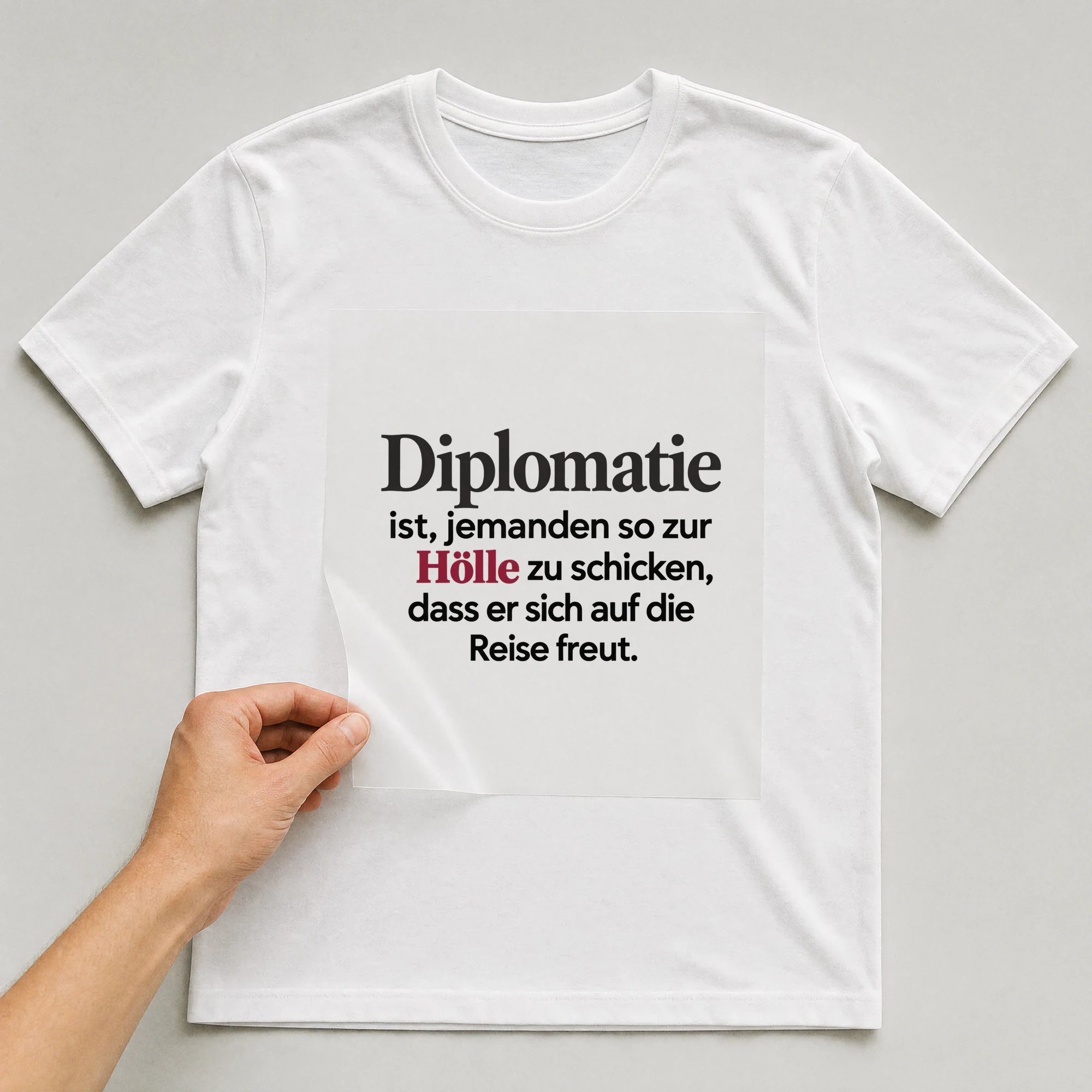 Bügelbild „Diplomatie ist, jemanden so zur Hölle zu schicken“ auf weißem T-Shirt, Folie wird aufgelegt