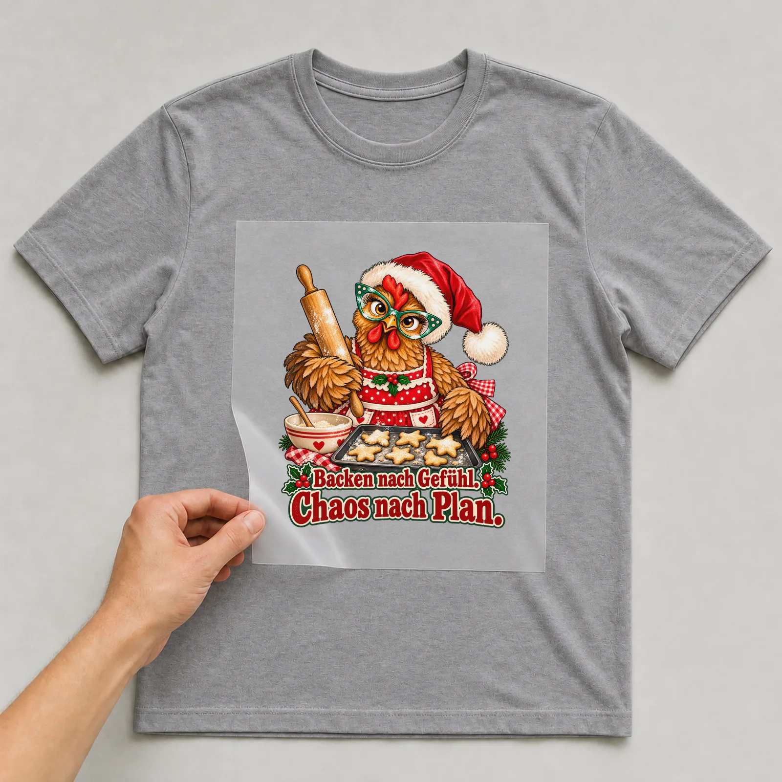 Bügelbild huhn plaetzchenbaecker auf grauem T-Shirt, Folie wird aufgelegt